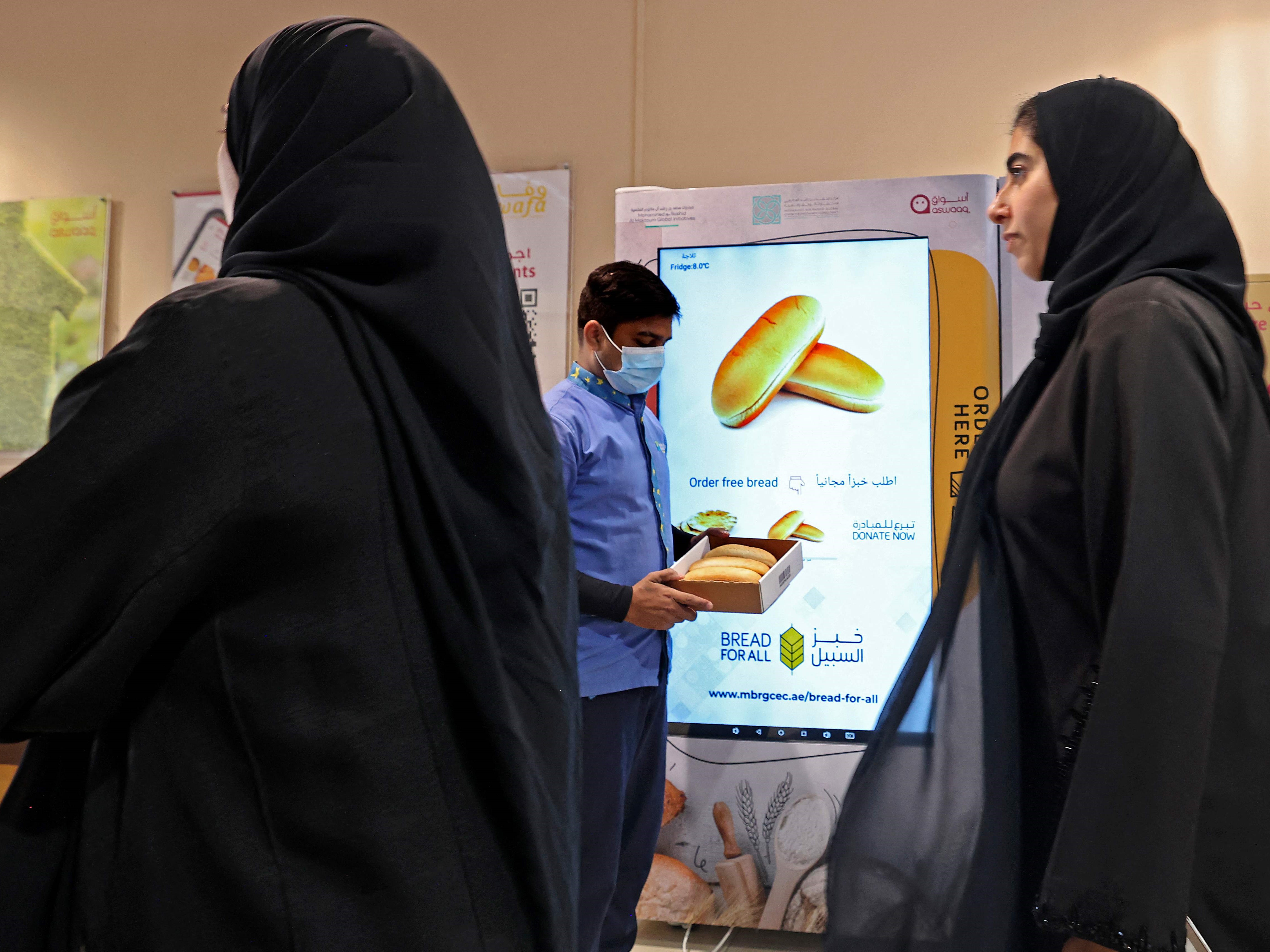 Seorang pria memegang kotak dari mesin penjual otomatis yang membagikan roti gratis di Dubai pada 22 September 2022.