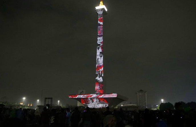 Pengunjung menyaksikan pertunjukan video mapping malam tahun baru di Monas, Jakarta, Selasa (31/12) malam.