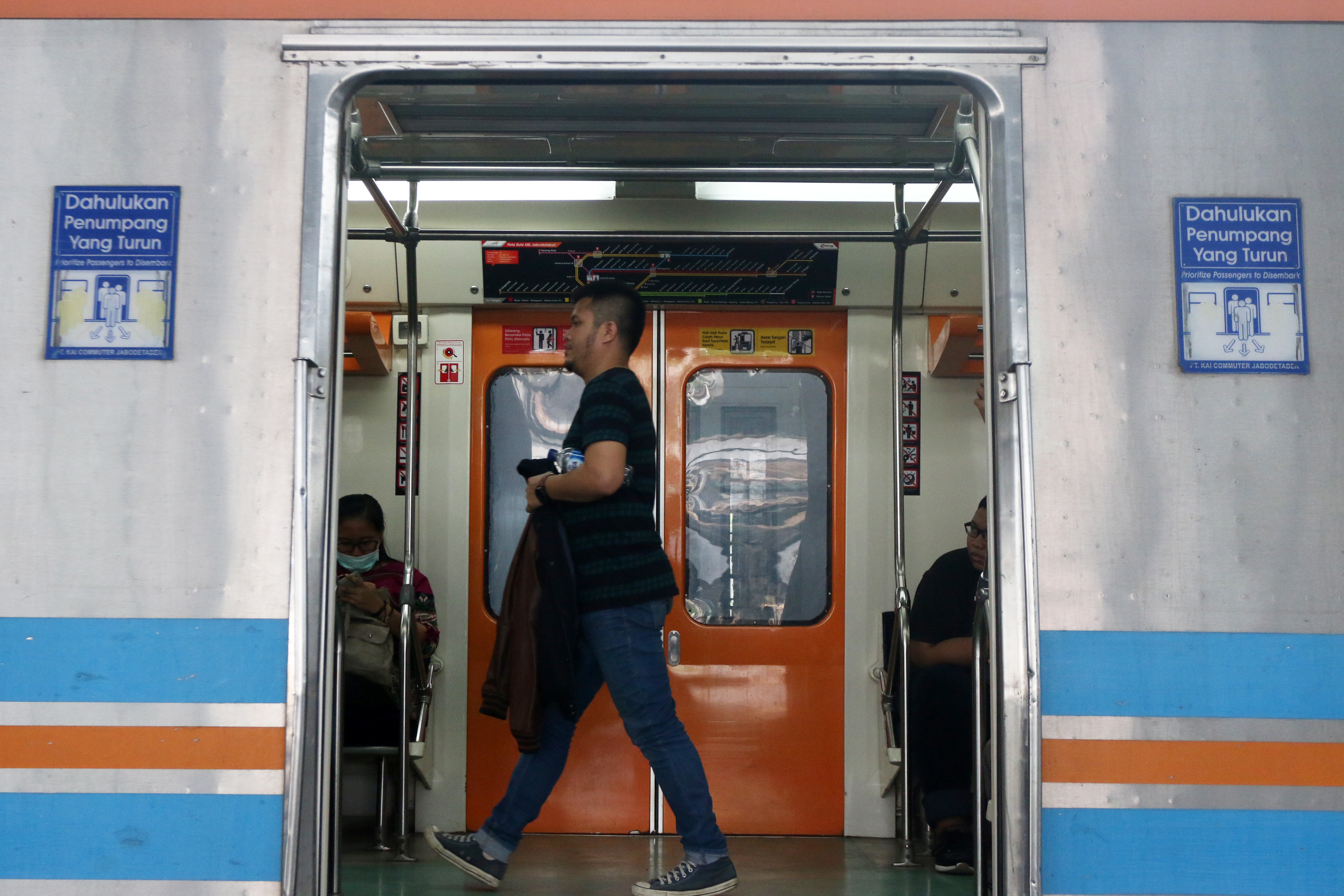 Penumpang berjalan di dalam gerbong Kereta Rel Listrik (KRL) di Stasiun Tanjung Priok, Jakarta