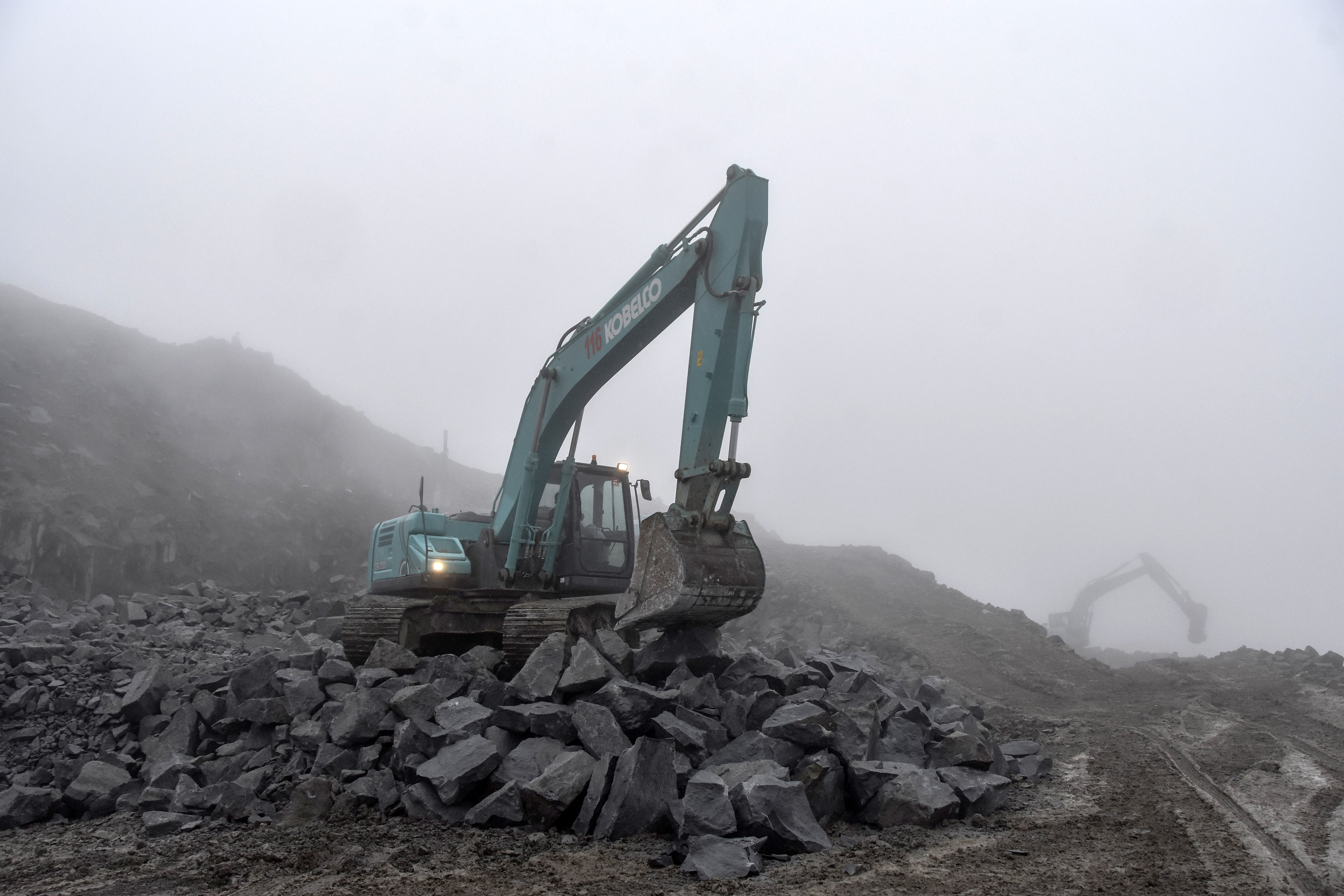 Pekerja menggunakan alat berat untuk mengangkut material pembangunan bendungan.