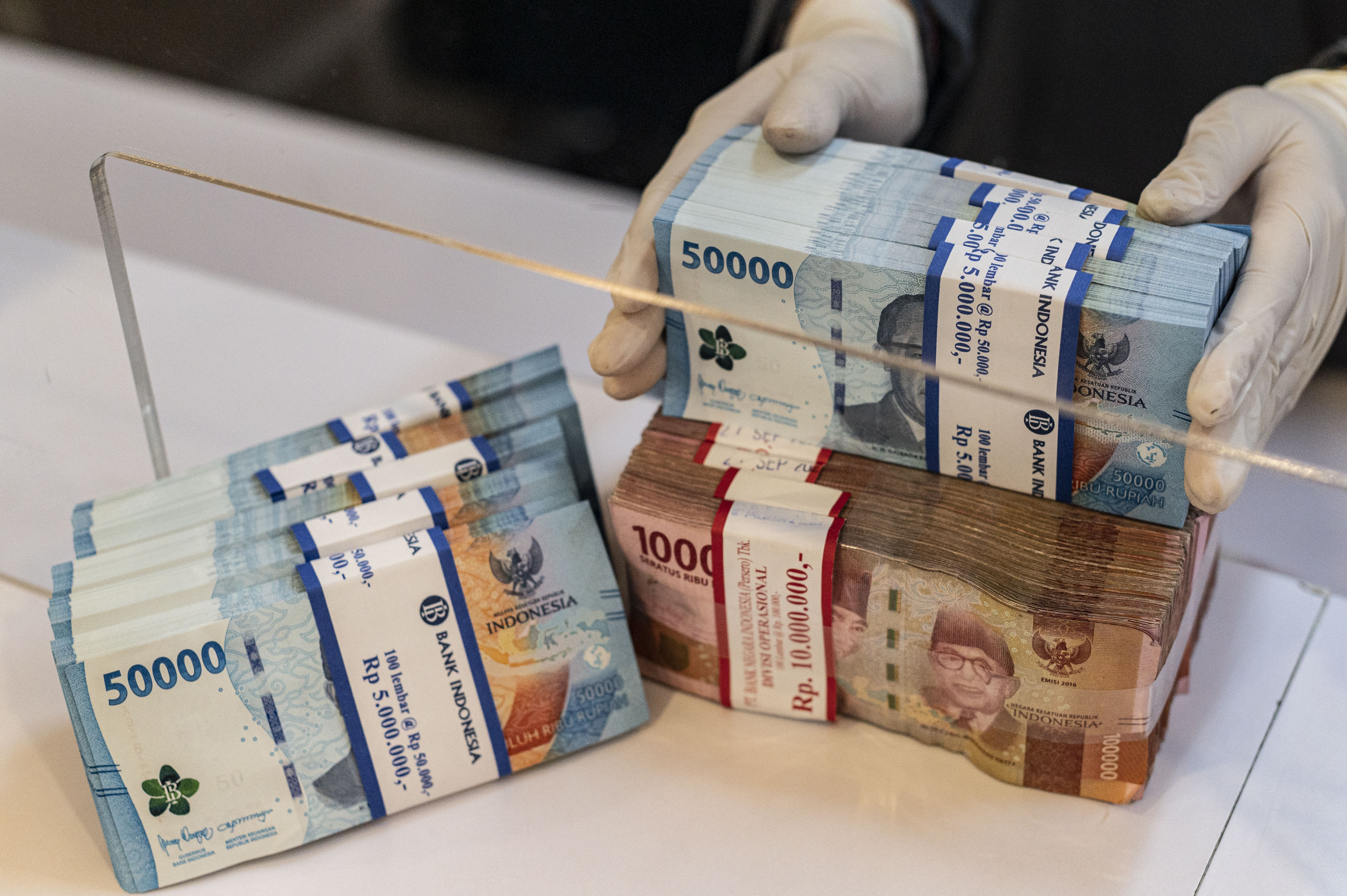 Potret karyawan bank menunjukkan uang pecahan rupiah.