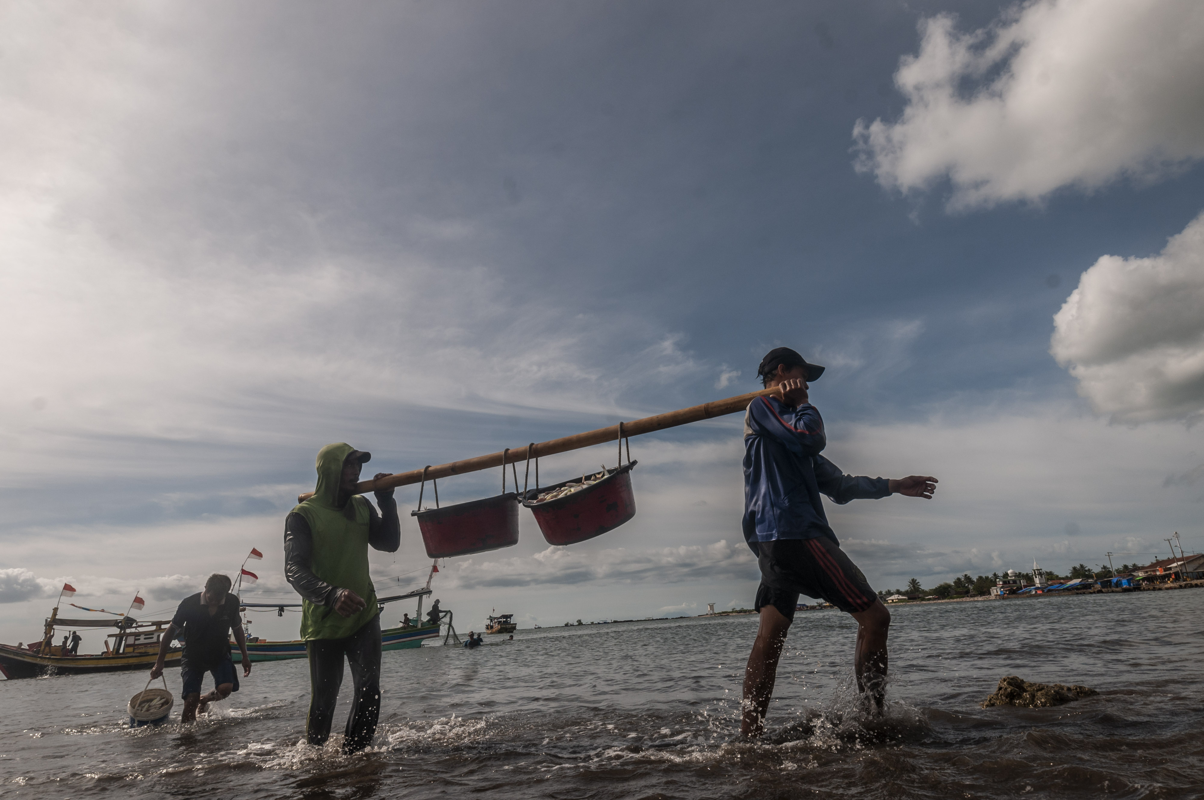 Potret nelayan membawa ikan hasil tangkapan.