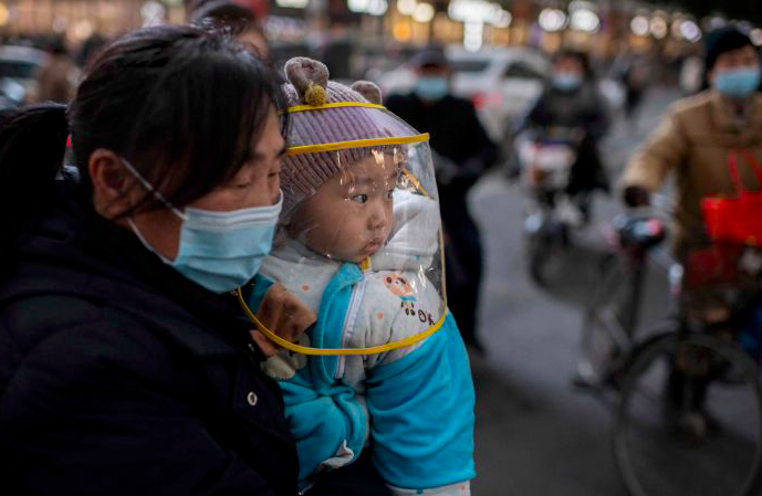 Seorang ibu menggendong bayinya di Wuhan, Tiongkok.