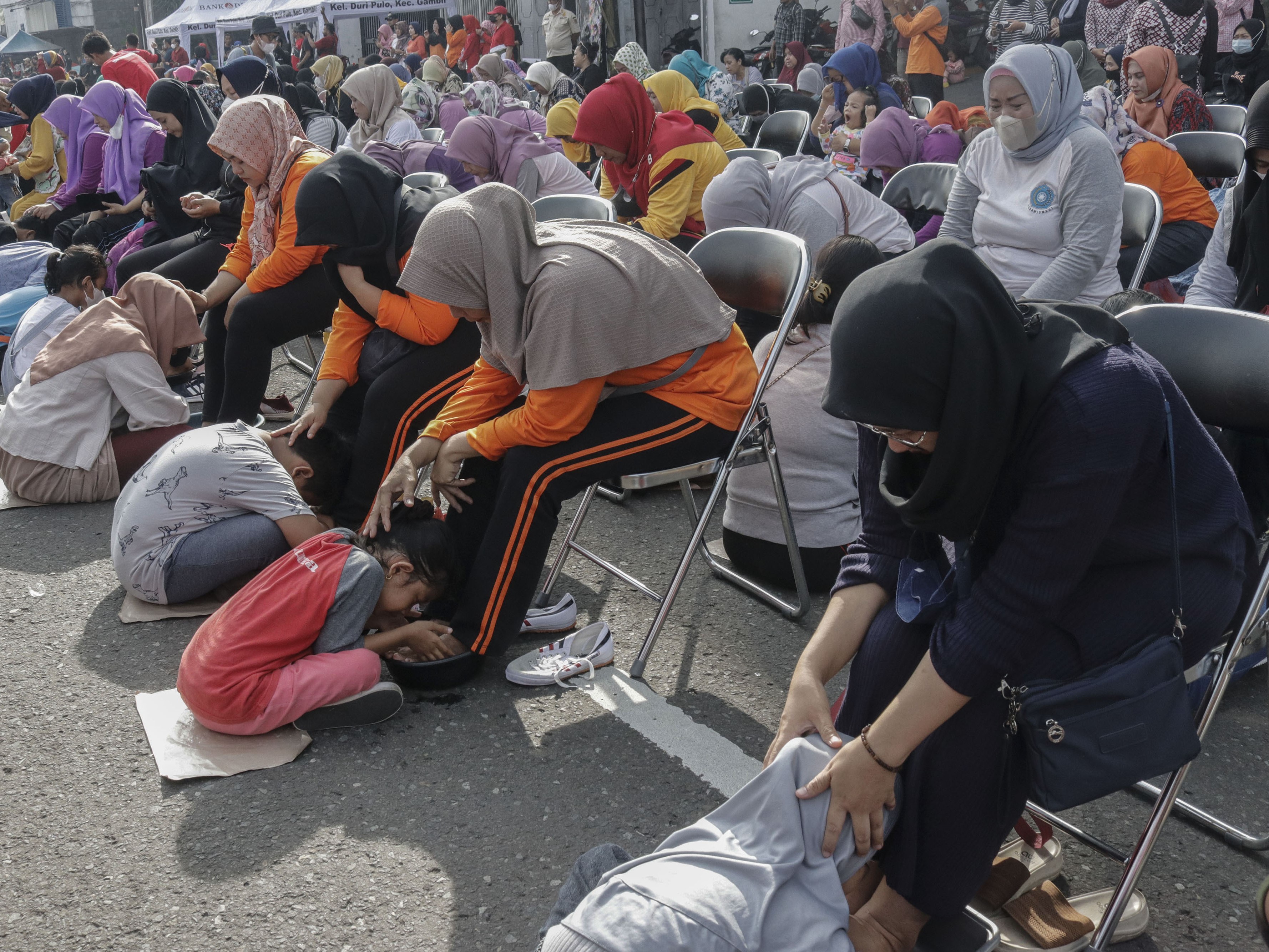 Sejumlah anak mencuci kaki ibu mereka dalam peringatan Hari Ibu di Jalan Suryapranoto, Gambir, Jakarta, Minggu (18/12/2022).