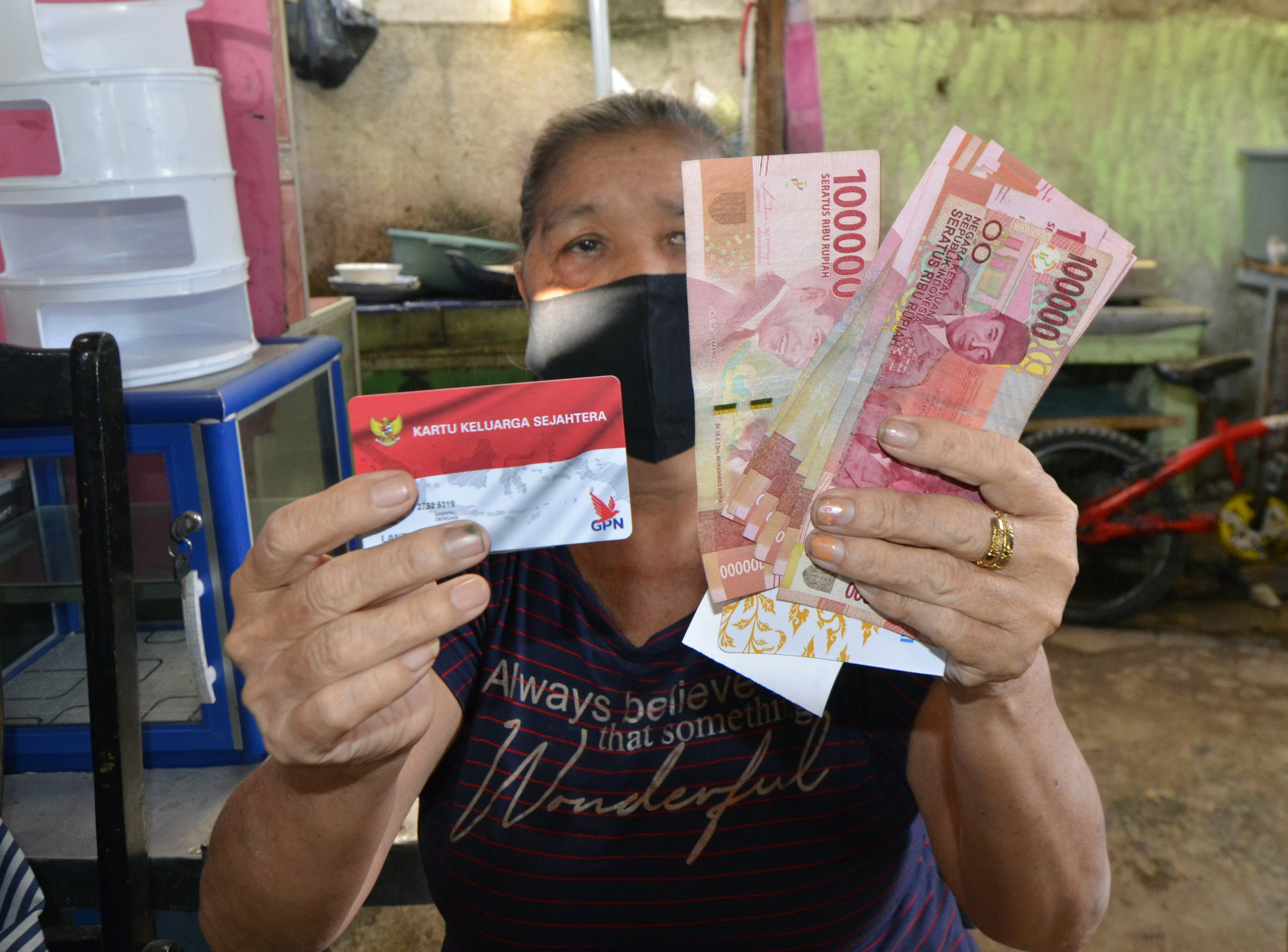 Warga menunjukkan uang bantuan yang diterimanya usai penyaluran Program Keluarga Harapan (PKH)