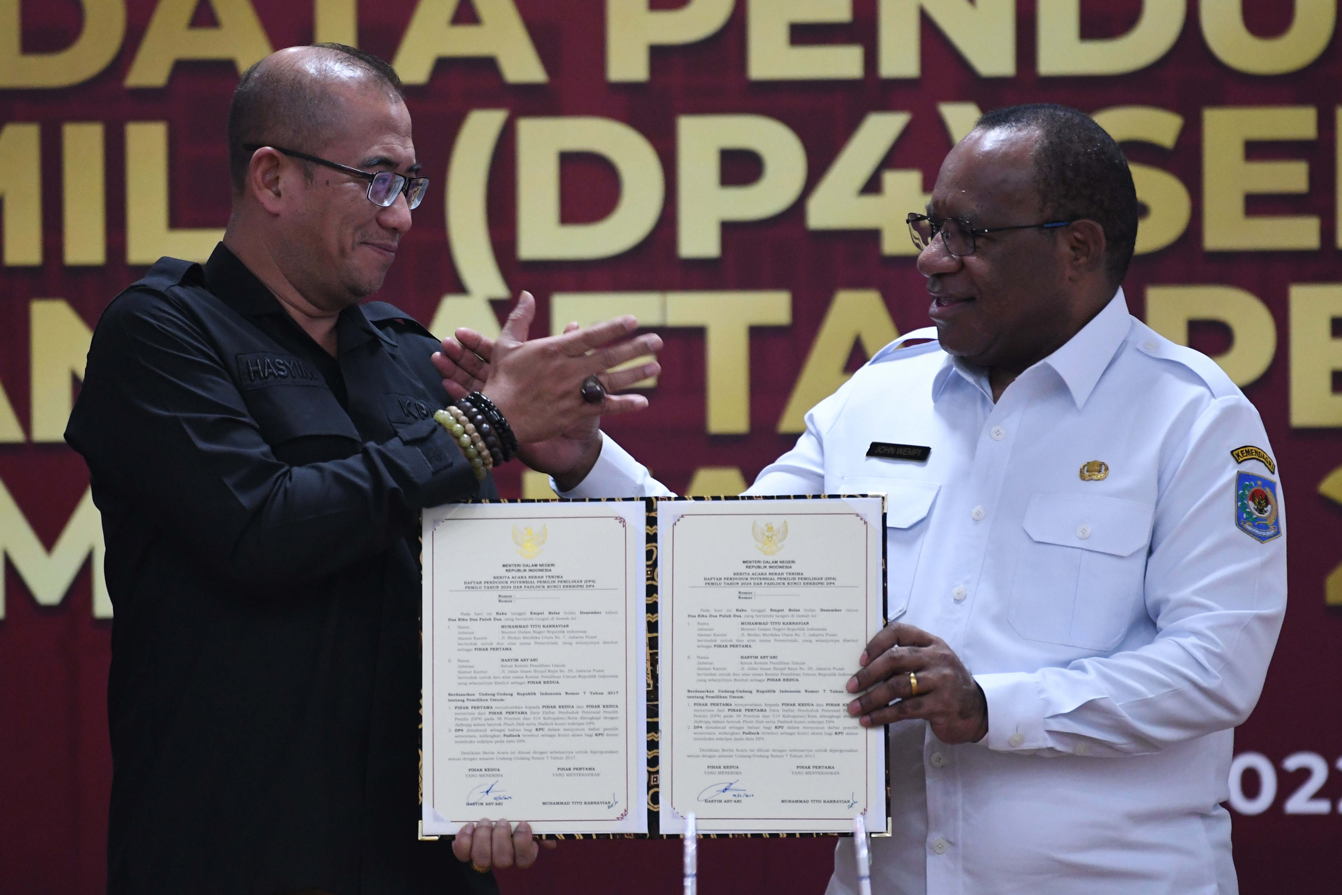 Ketua KPU Hasyim Asy'ari (kiri) berjabat tangan dengan Wamendagri John Wempi Wetipo (kanan) saat penyerahan Data Penduduk Potensial Pemilih 