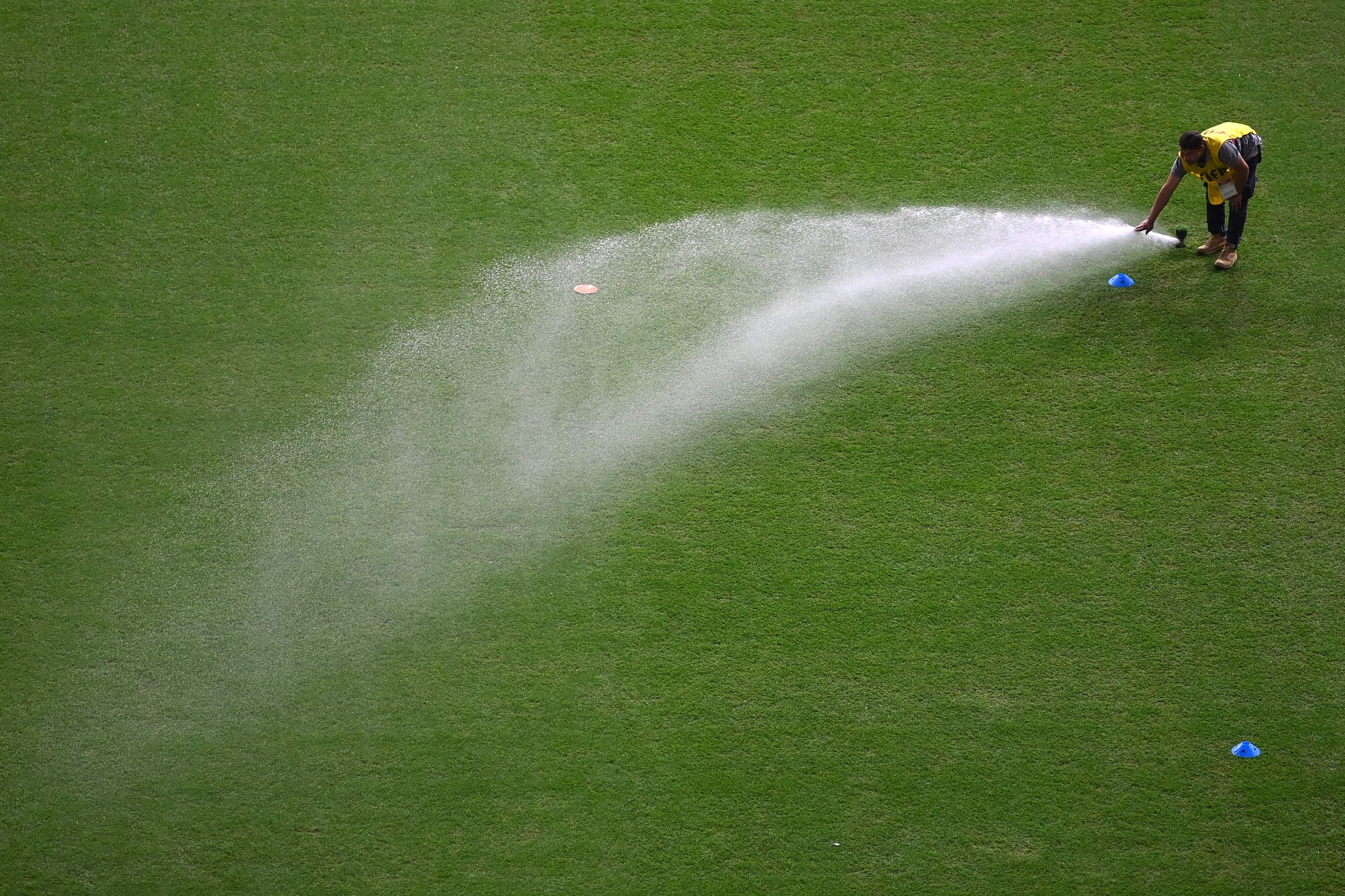 Air disemprotkan ke lapangan yang digunakan sebagai tempat berlatih dan bertanding di Piala Dunia 2022