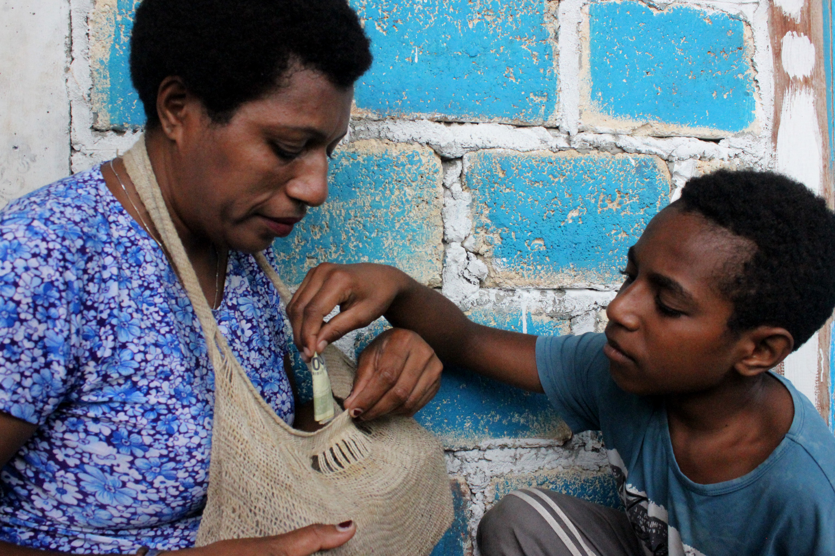 Seorang anak menabung uang rupiah kertas ke dalam wadah noken yang dibuat khusus oleh orang tuanya, di Papua.