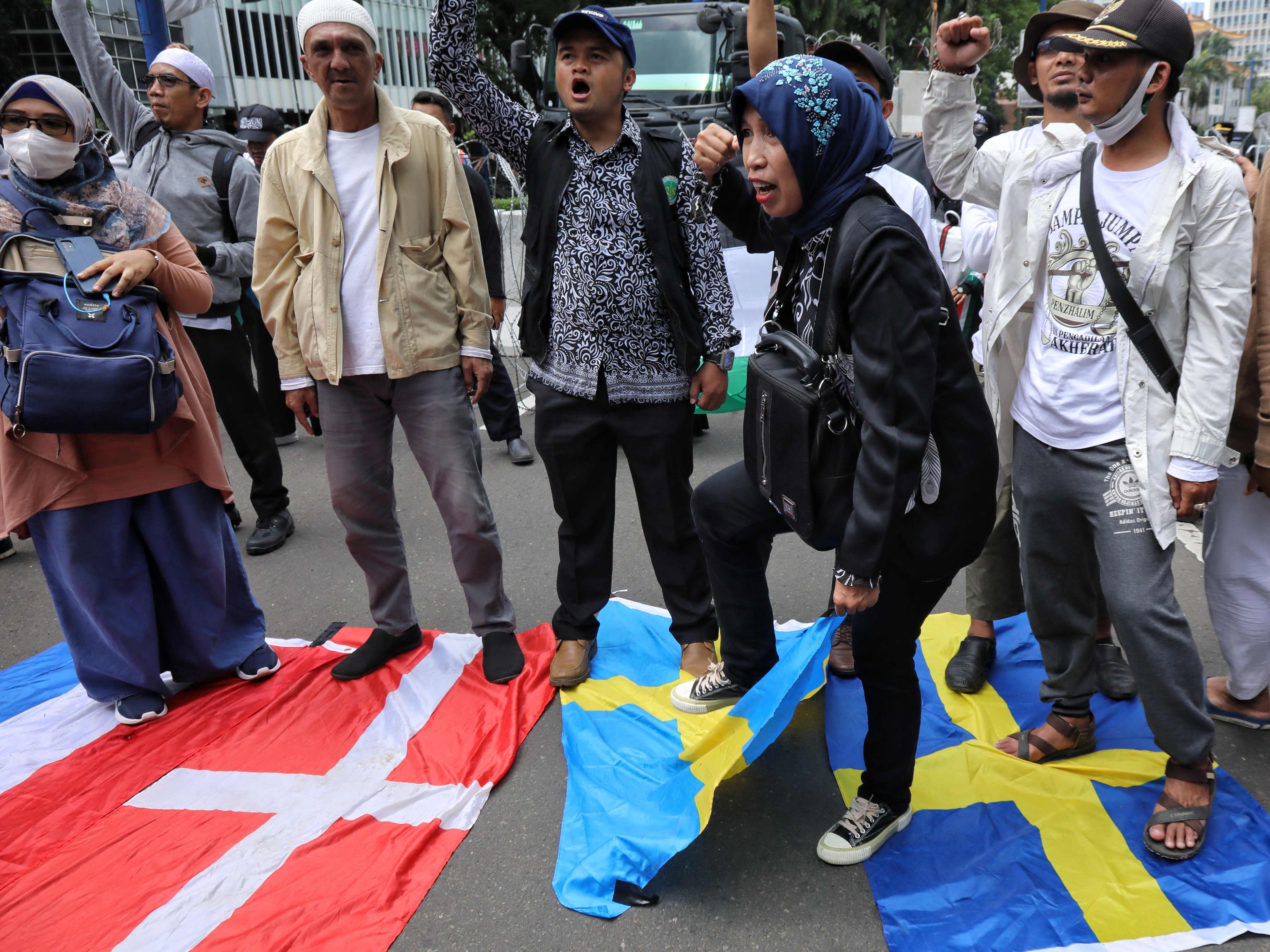 Aktivis menginjak bendera Denmark dan Swedia saat para demonstran berkumpul di luar Kedutaan Besar Swedia di Jakarta pada 30 Januari 2023.