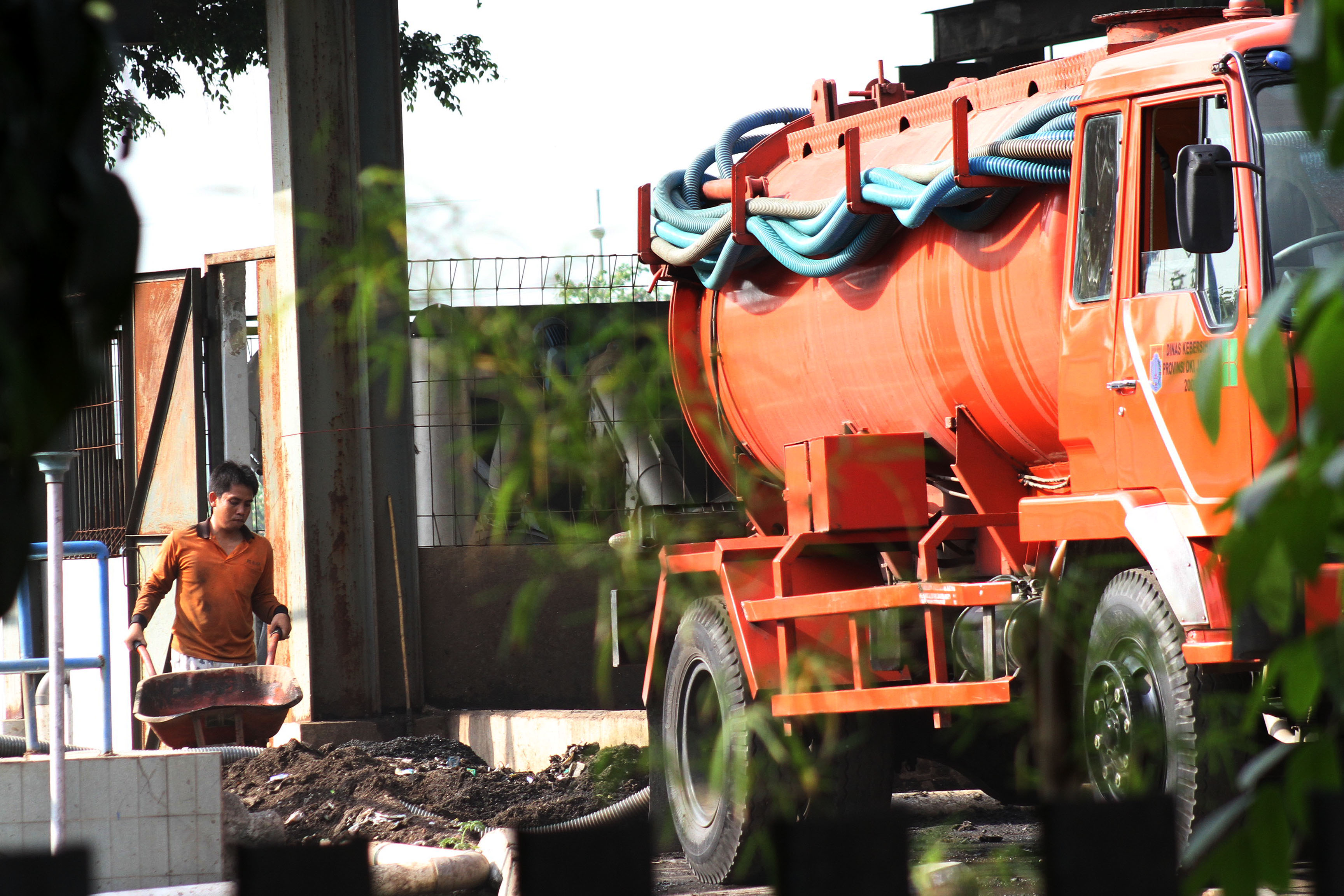 Ilustrasi petugas membersihkan tangki mobil tinja.