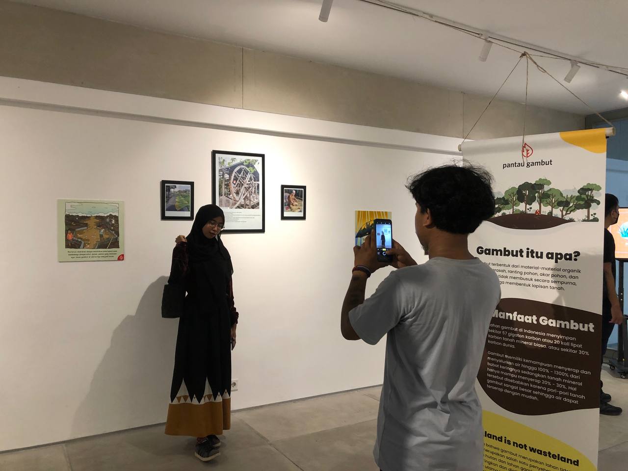 Seorang pengunjung berpose di depan karya pada pameran seni mengenai lahan gambut di Jakarta, Sabtu (14/1)