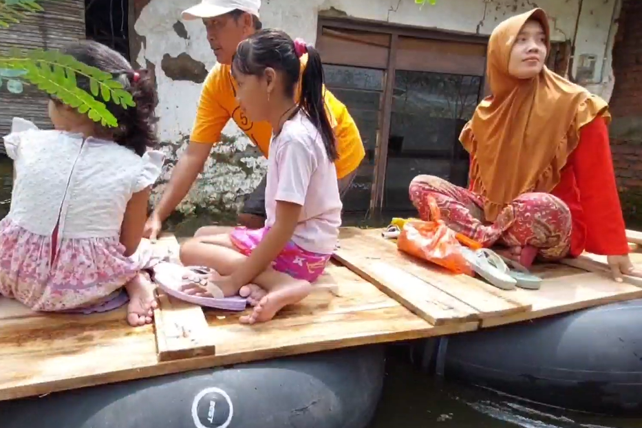 Warga naik perahu papan kayu di tengah banjir.