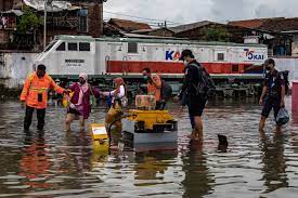 Karyawan KAI membantu sejumlah penumpang menembus banjir untuk keluar dari Stasiun Tawang yang terendam banjir di Semarang, Jawa Tengah.