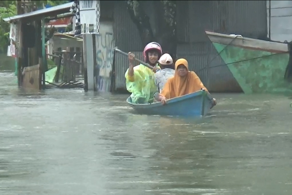 Warga Maros naik perahu di tengah banjir.