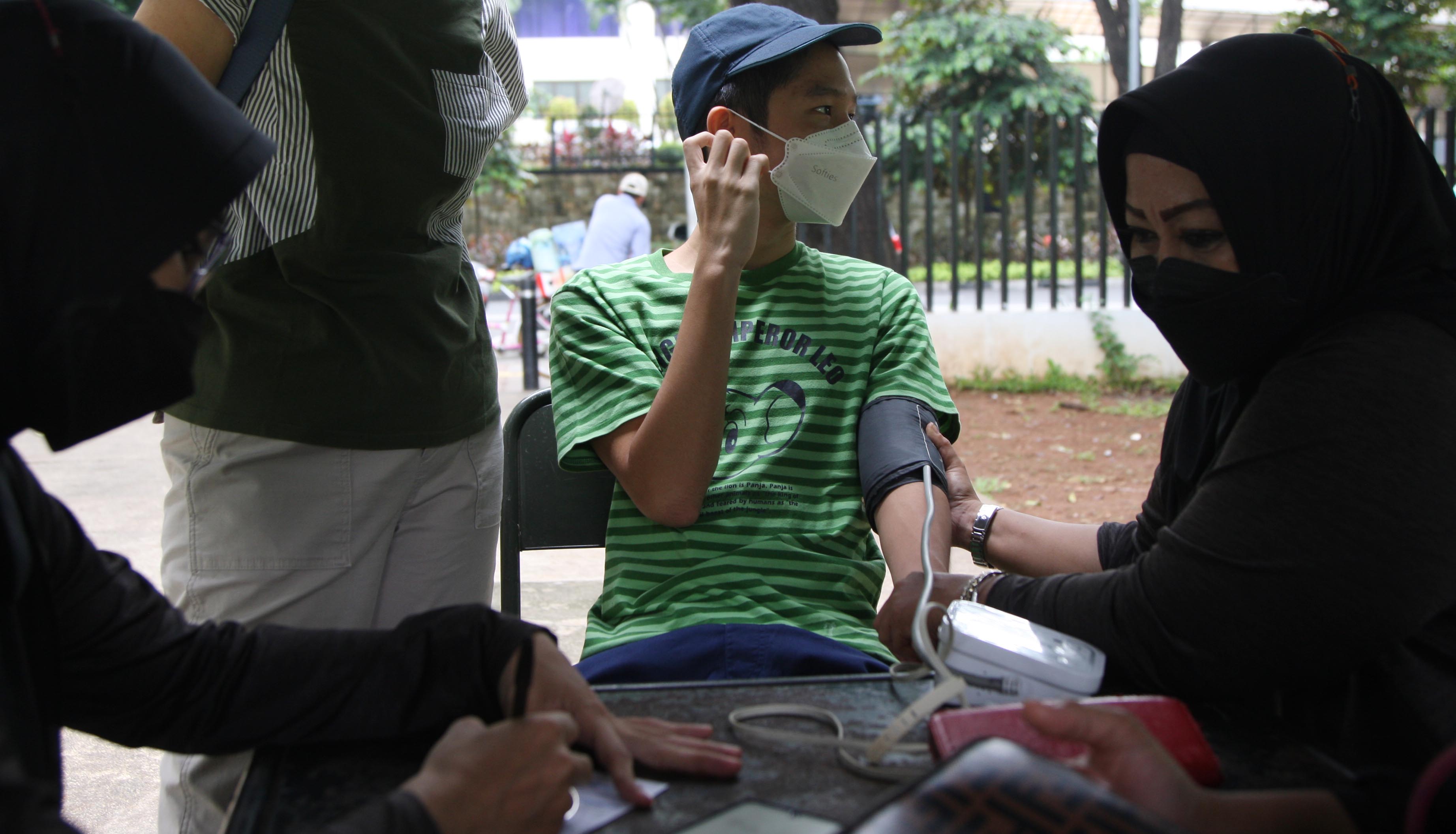 Petugas kesehatan mengukur suhu tubuh warga sebelum suntik vaksin booster covid-19 di Taman Lapangan Banteng, Jakarta, Rabu (4/1/2022).