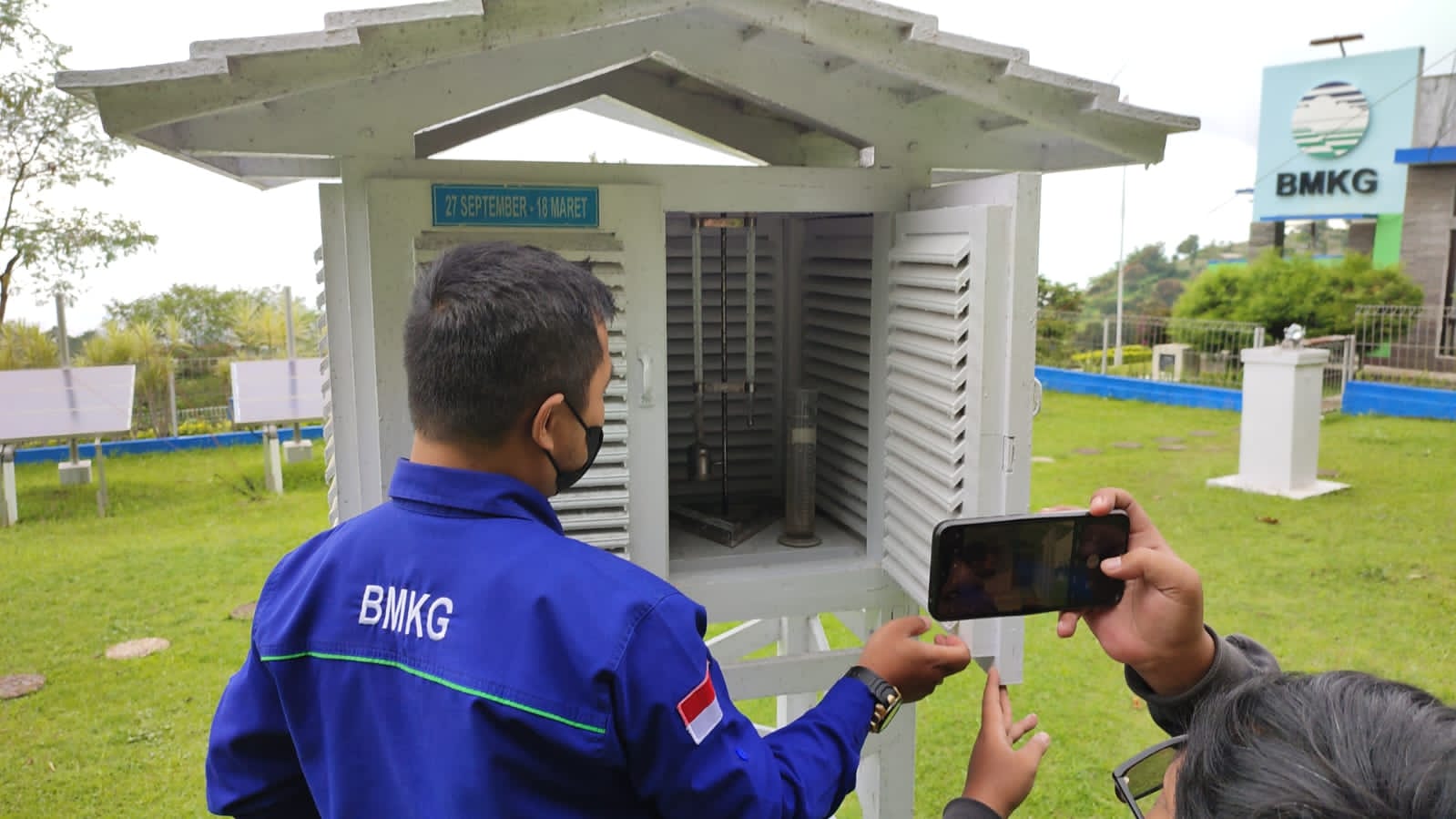 Petugas BMKG sedang mengecek alat pengukur/penakar hujan.