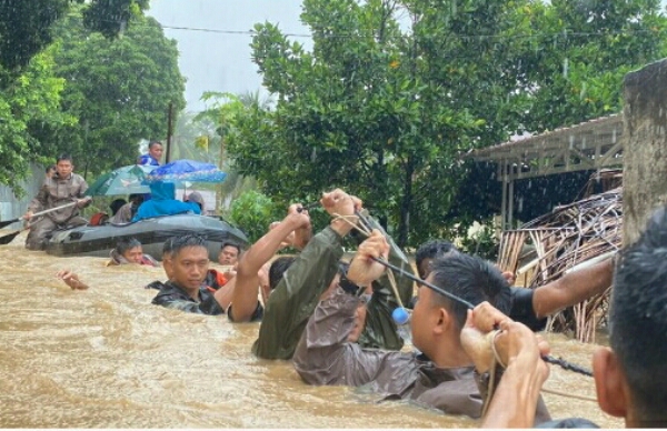 Anggota Brimob Polda Sulawesi Utara mengevakuasi warga yang rumahnya dikepung banjir
