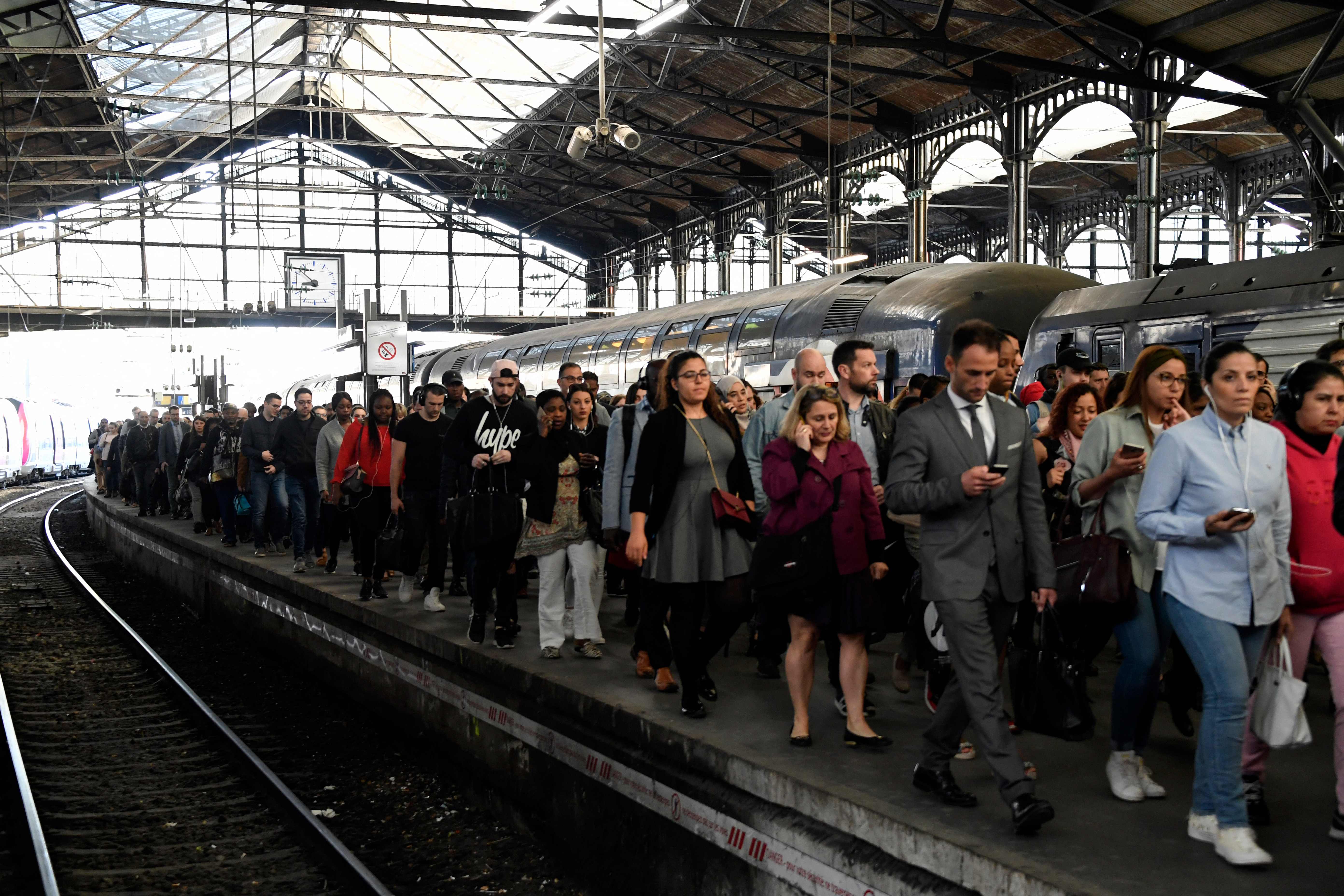 Para pekerja lintas kota Prancis berjalan di Stasiun Metro Saint-Lazare, Paris.