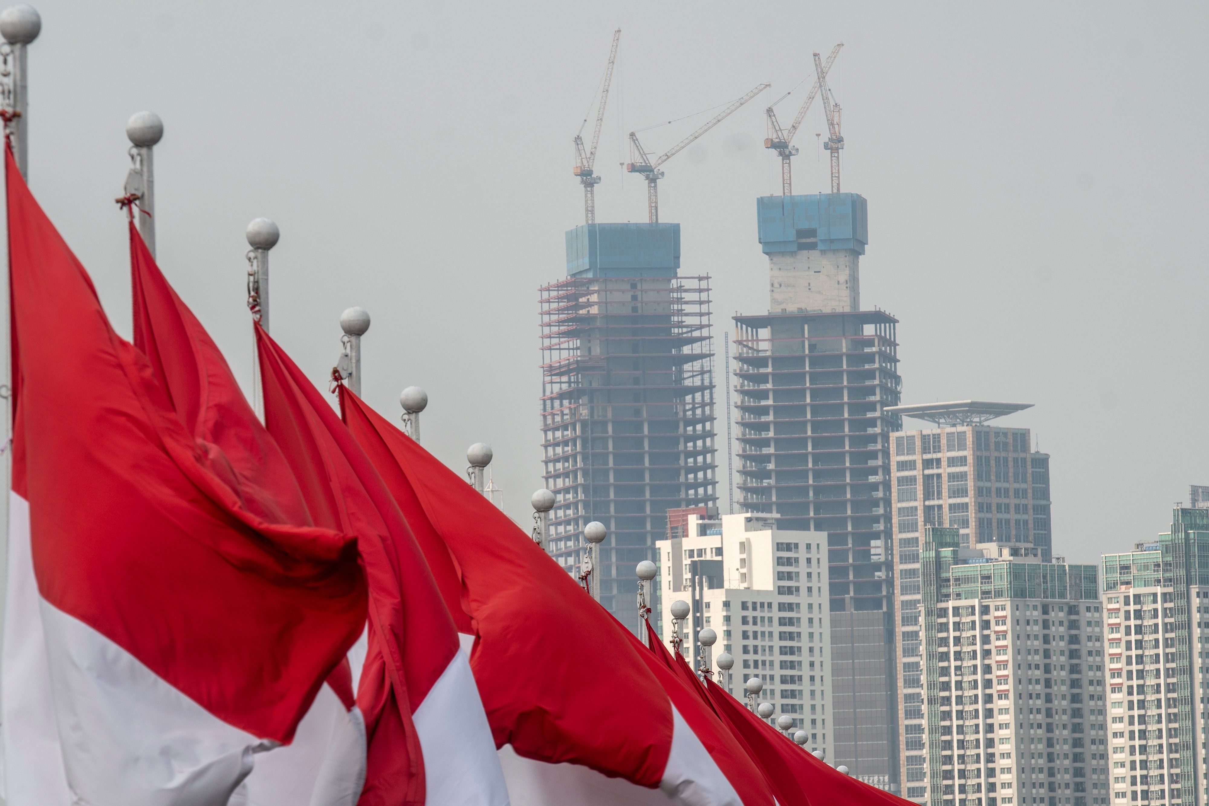 Deretan bendera Merah Putih dengan latar belakang gedung bertingkat di Jakarta.