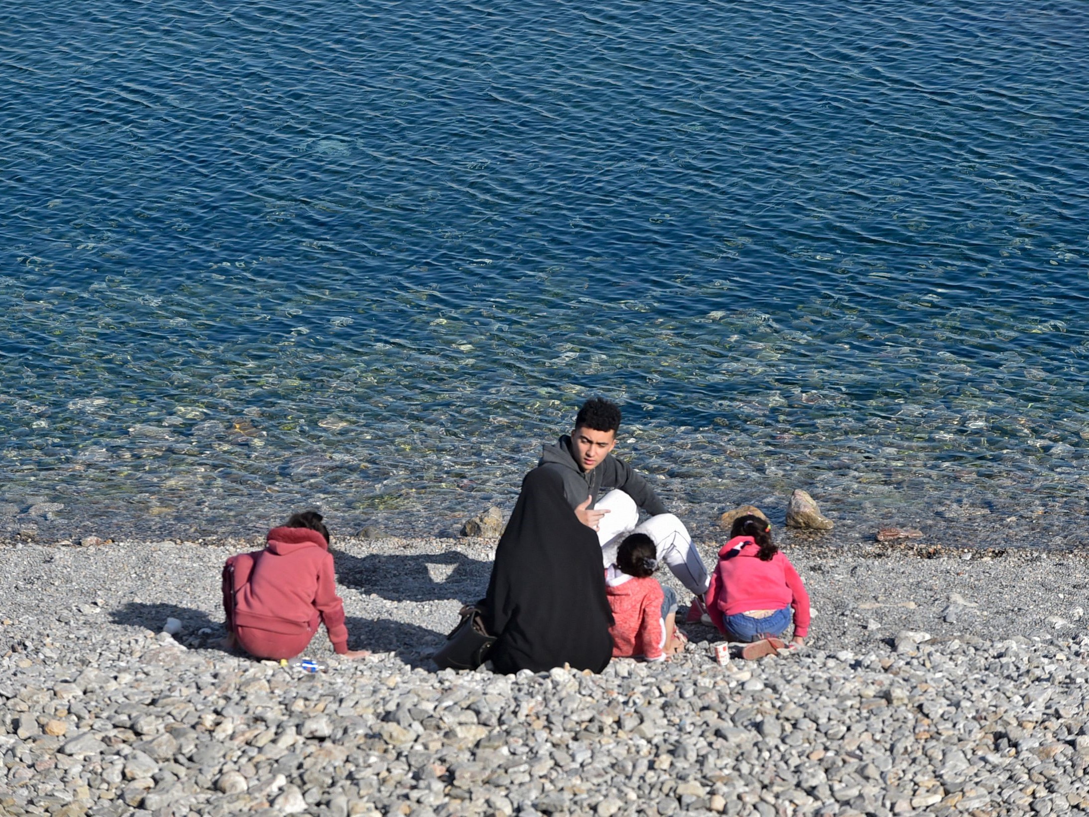 Satu keluarga duduk di tepi pantai saat cuaca bagus di Aljazair pada 2 Januari 2023.