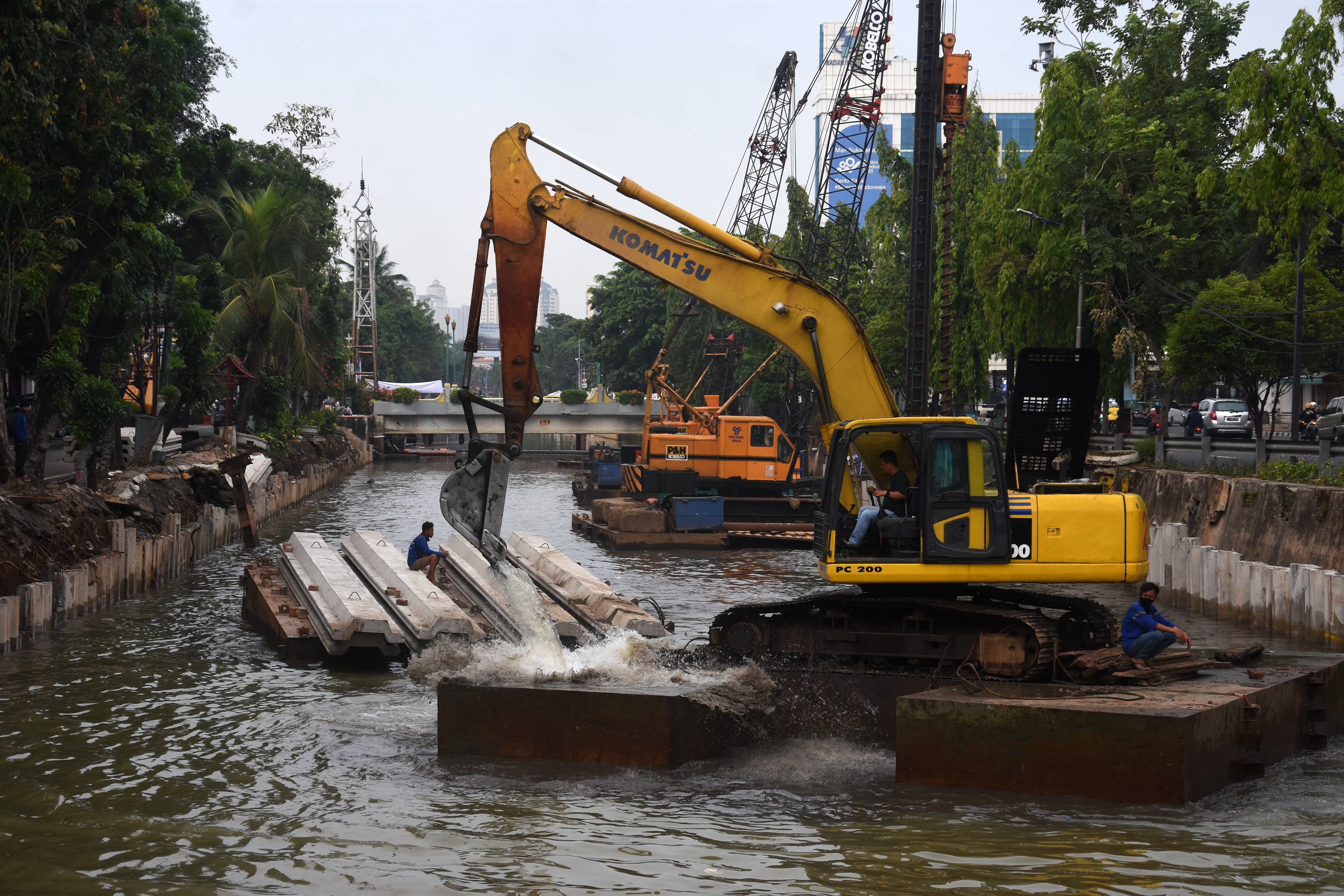 Sejumlah petugas menggunakan alat berat saat menyelesaikan pembangunan turap anak kali Cilwung di kawasan Pasar Baru, Jakarta.