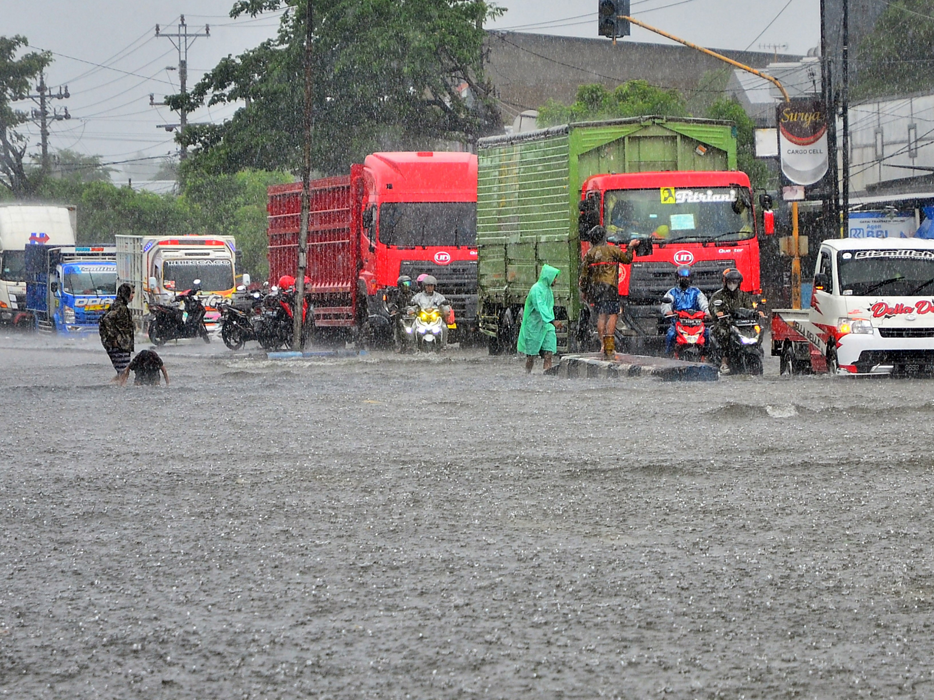 Sejumlah kendaraan menerobos jalan yang tergenang banjir di jalan Jalur Pantura Desa Jati Wetan, Kudus, Jawa Tengah, Minggu (1/1/2023).