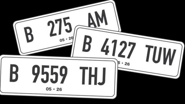 Pelat nomor kendaraan berwarna putih.