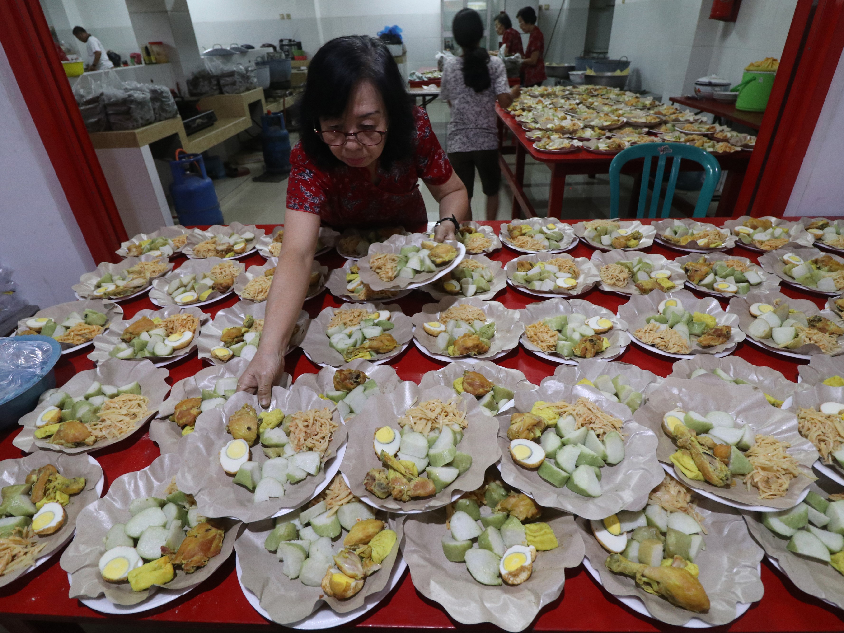 Warga Tionghoa menyiapkan lontong beserta lauk pauknya kedalam piring di Kelenteng Tjoe Hwie Kiong di Kota Kediri, Jawa Timur.