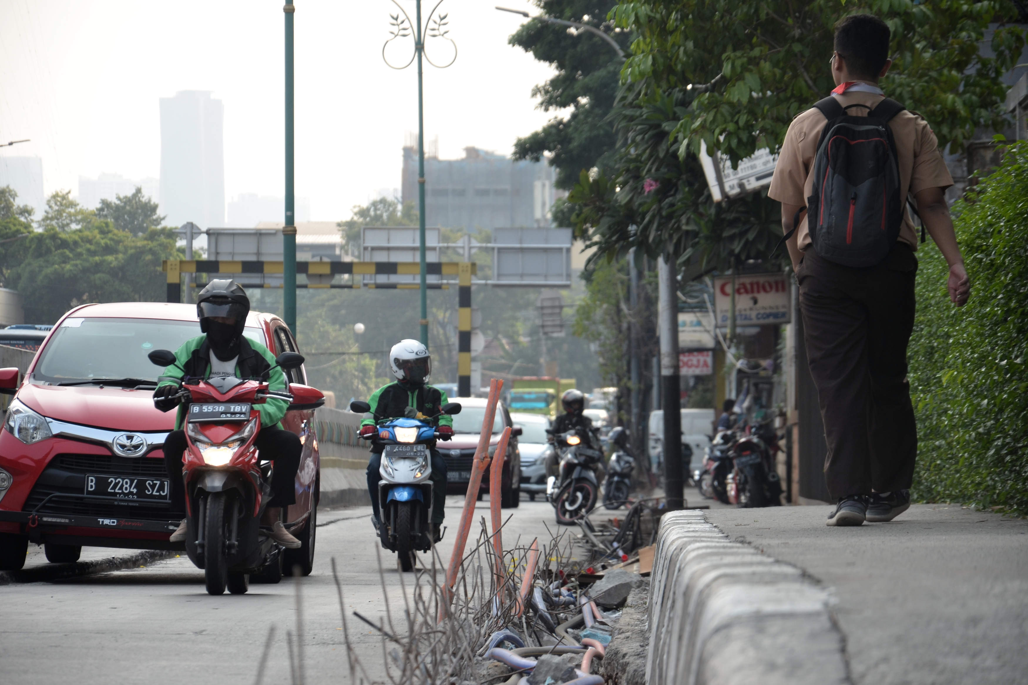 Pengendara melintas di sebelah galian kabel utilitas tanpa pengaman di wilayah Jakarta.