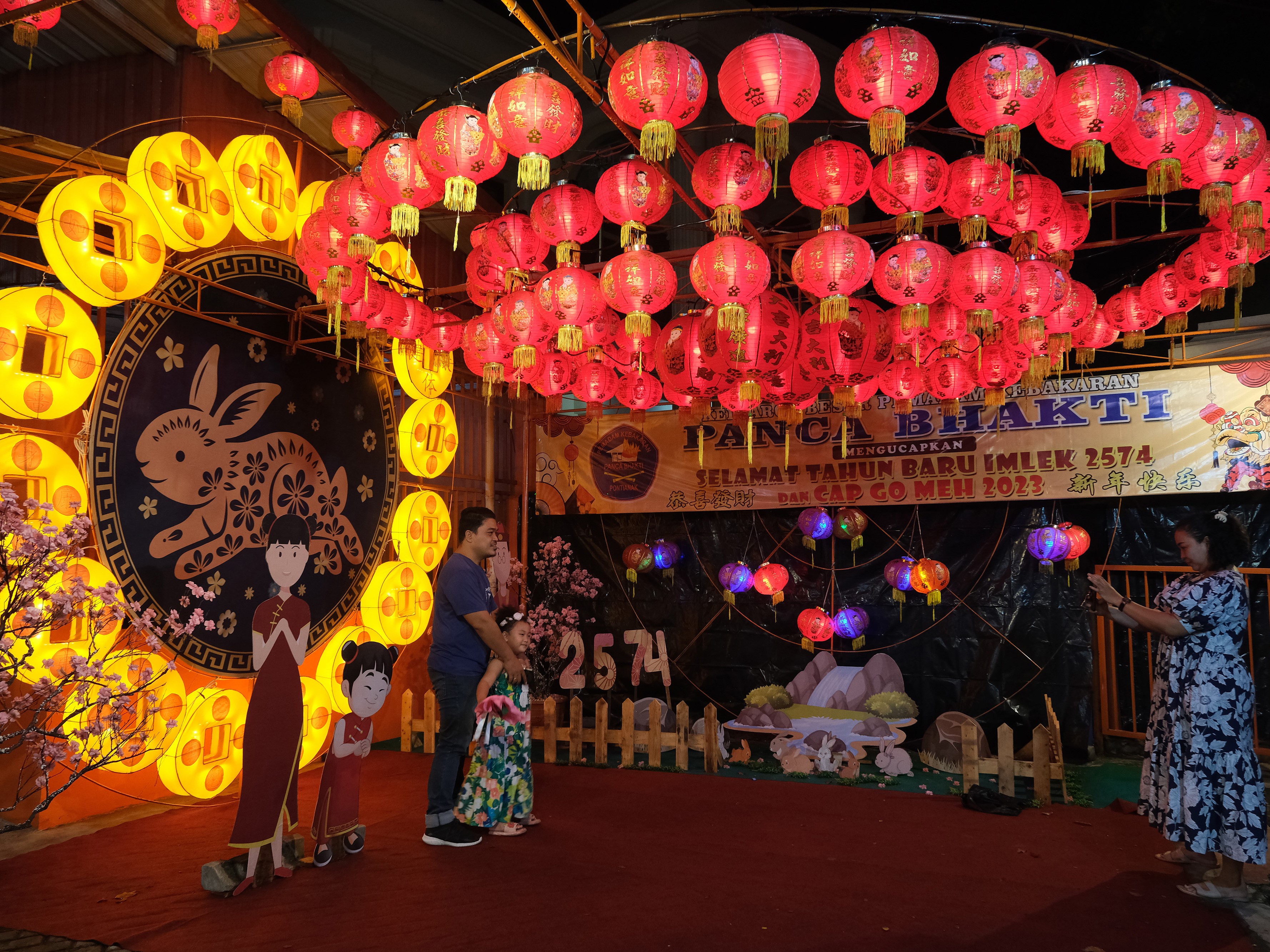Tiga warga berfoto di kawasan yang disemarakkan dengan hiasan Imlek di halaman Posko Pemadam Kebakaran (Damkar) Panca Bhakti di Pontianak.