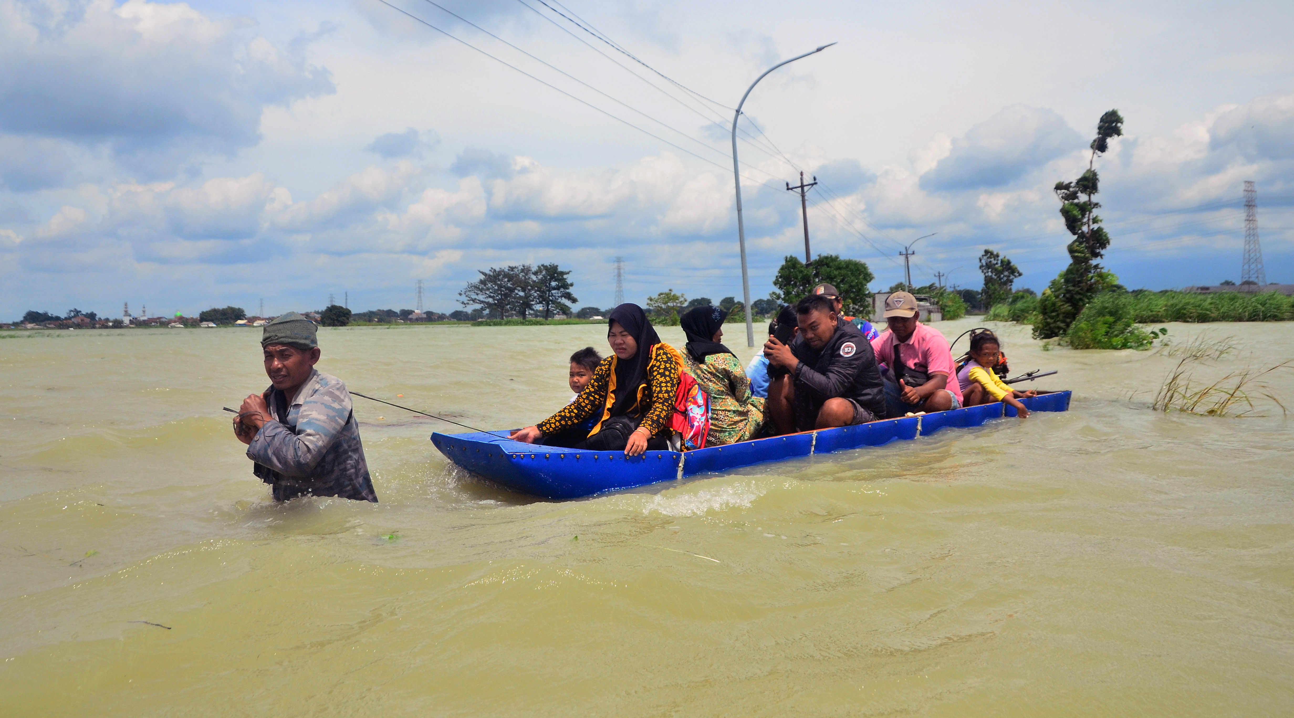 Warga menggunakan perahu melintasi jalan yang tergenang banjir di Karangturi, Setrokalangan, Kudus, Jawa Tengah, Selasa (3/1).