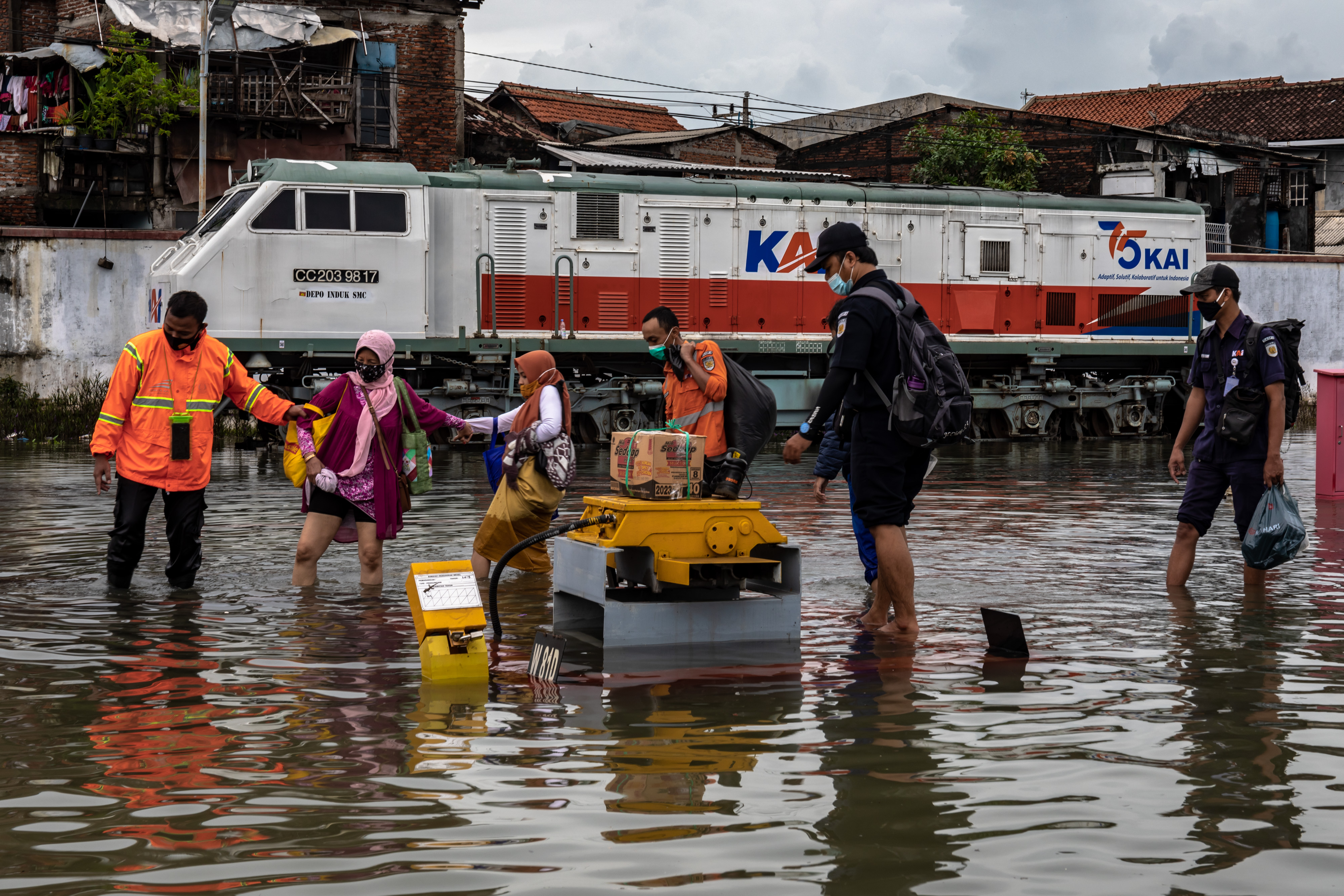Karyawan KAI membantu sejumlah penumpang menembus banjir untuk keluar dari Stasiun Tawang yang terendam banjir di Semarang, Jawa Tengah,