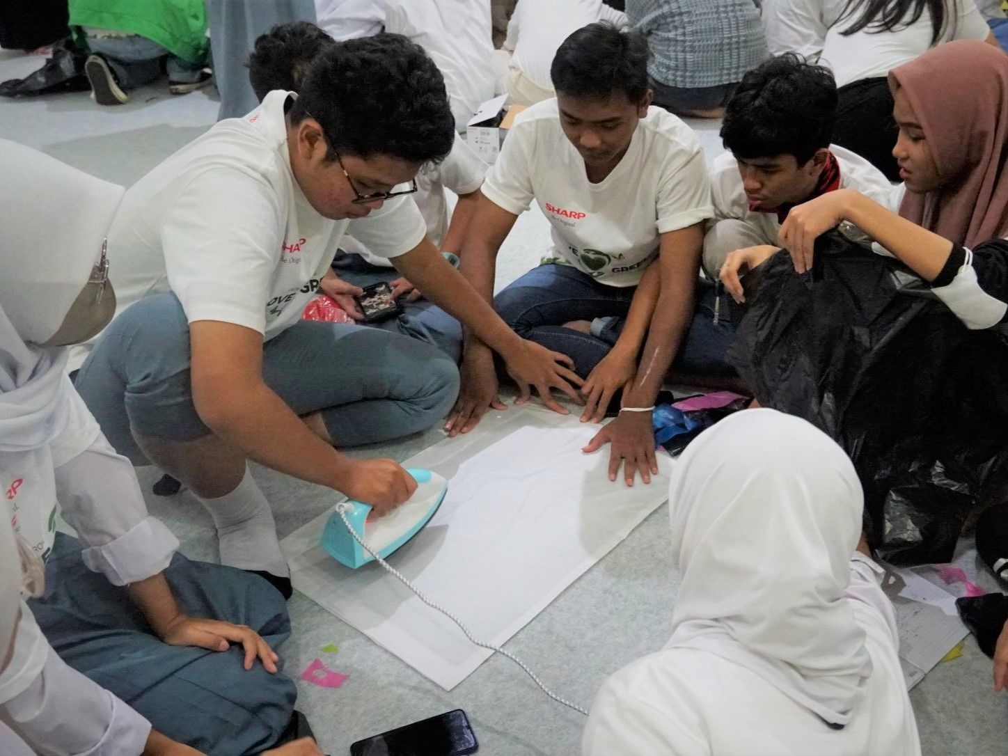 Peserta Sharp Eco-Bition sedang mendaur ulang sampah menjadi barang ergonomis.