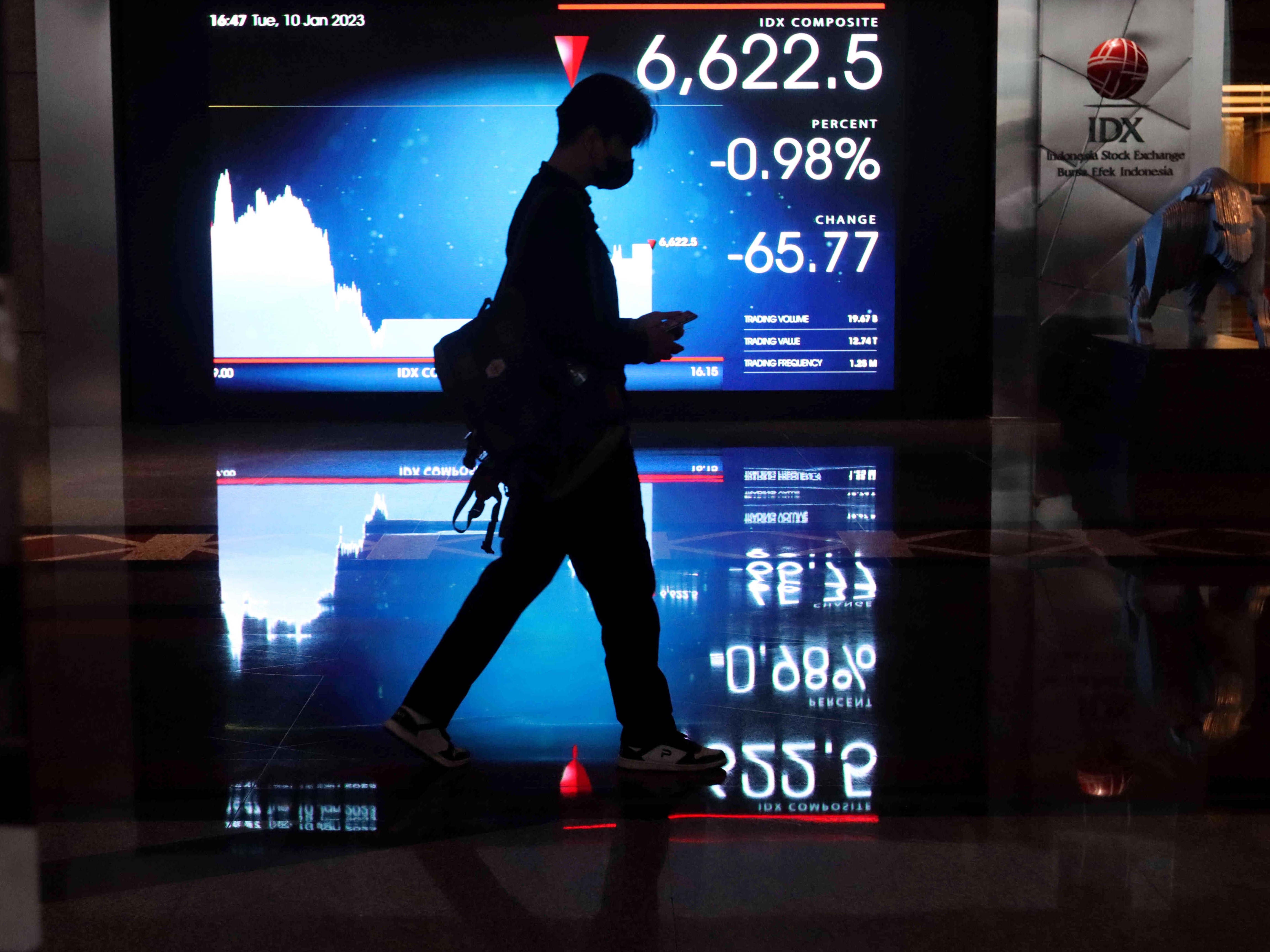 Warga melintas di dekat monitor pergerakan perdagangan saham di Bursa Efek Indonesia (BEI), Jakarta, Selasa (10/1/2023).