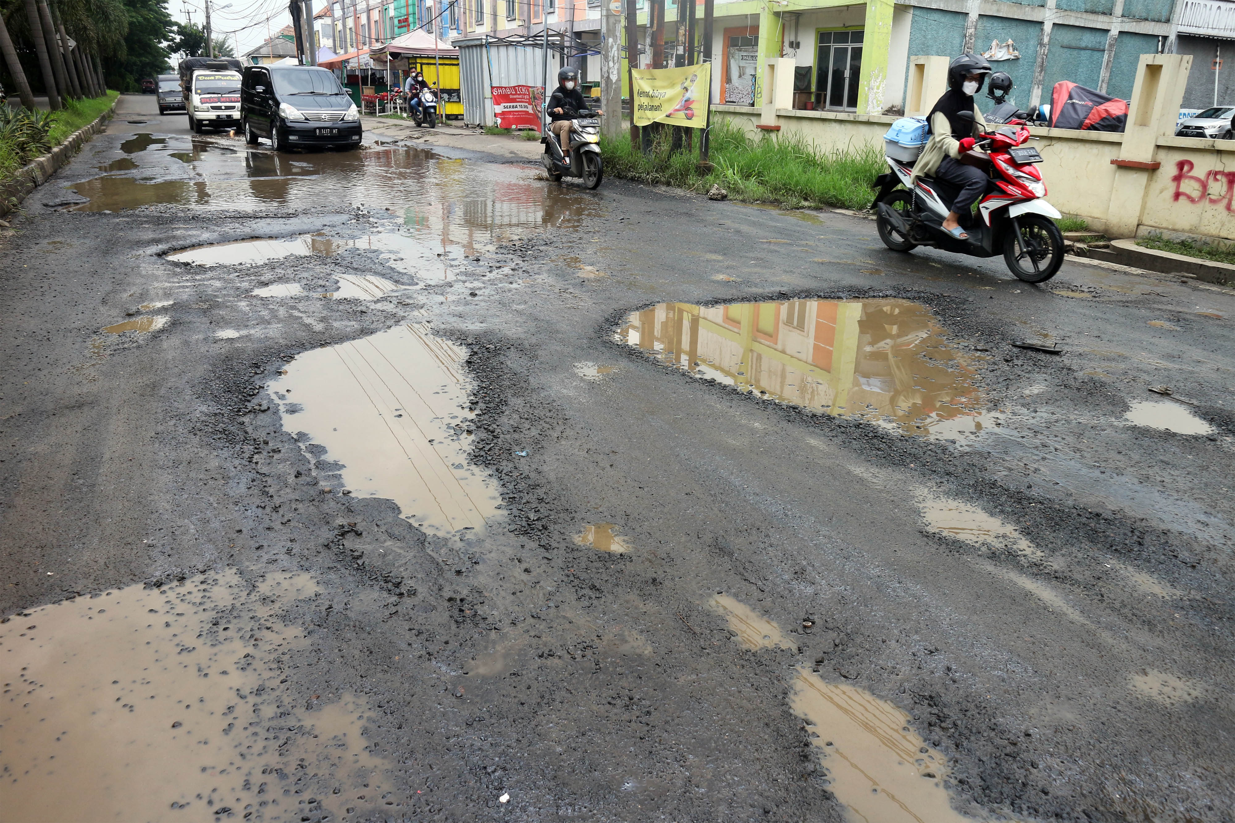 ejumlah kendaraan melintasi jalan berlubang dan tergenang air di Jalan Raya Tegar Beriman, Cibinong, Kabupaten Bogor, Jawa Barat.