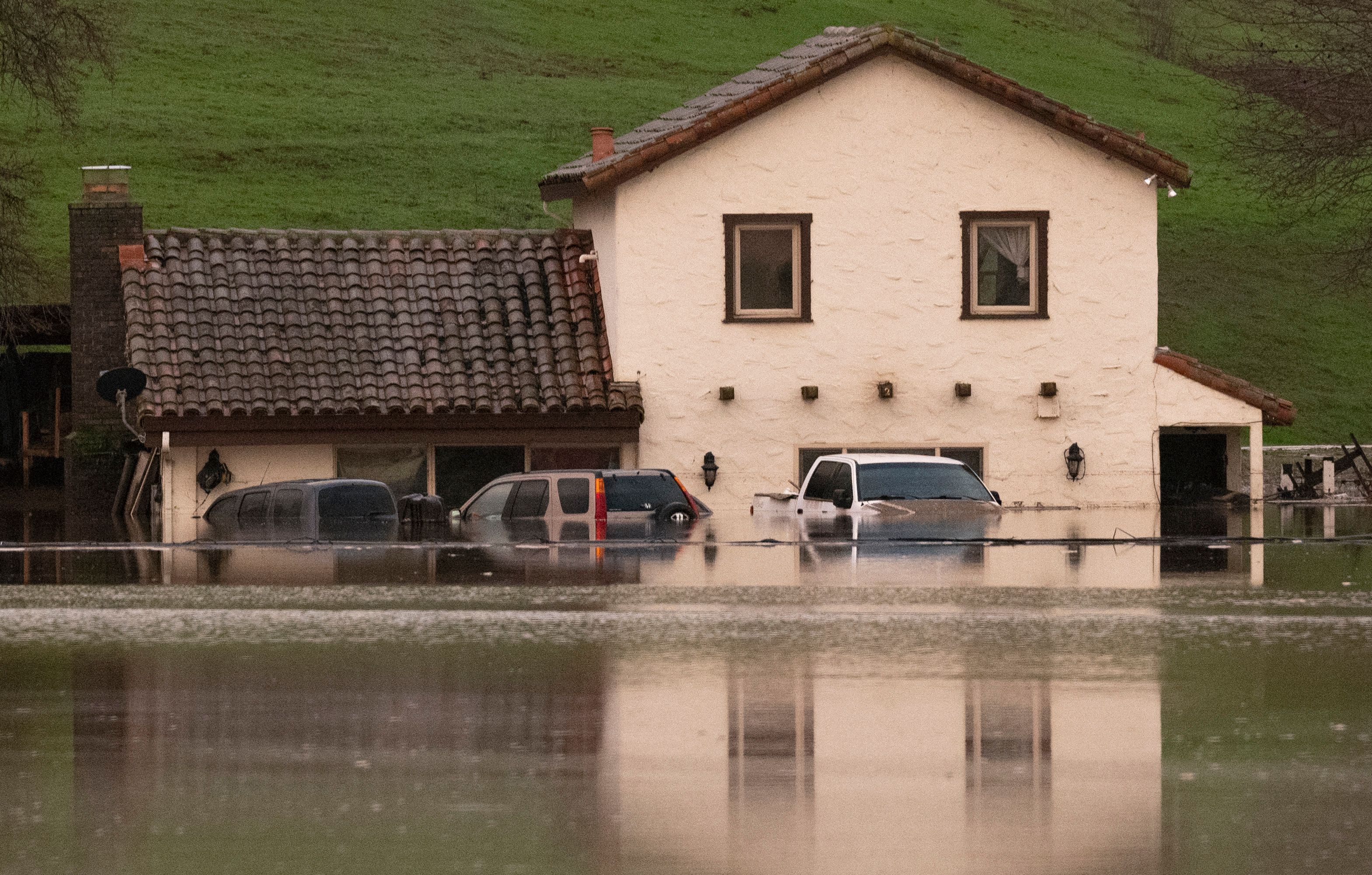 Tampak kendaraan teredam air dan rumah yang sebagian terendam banjir di Gilroy, California, Amerika Serikat, Senin (9/1/2023).