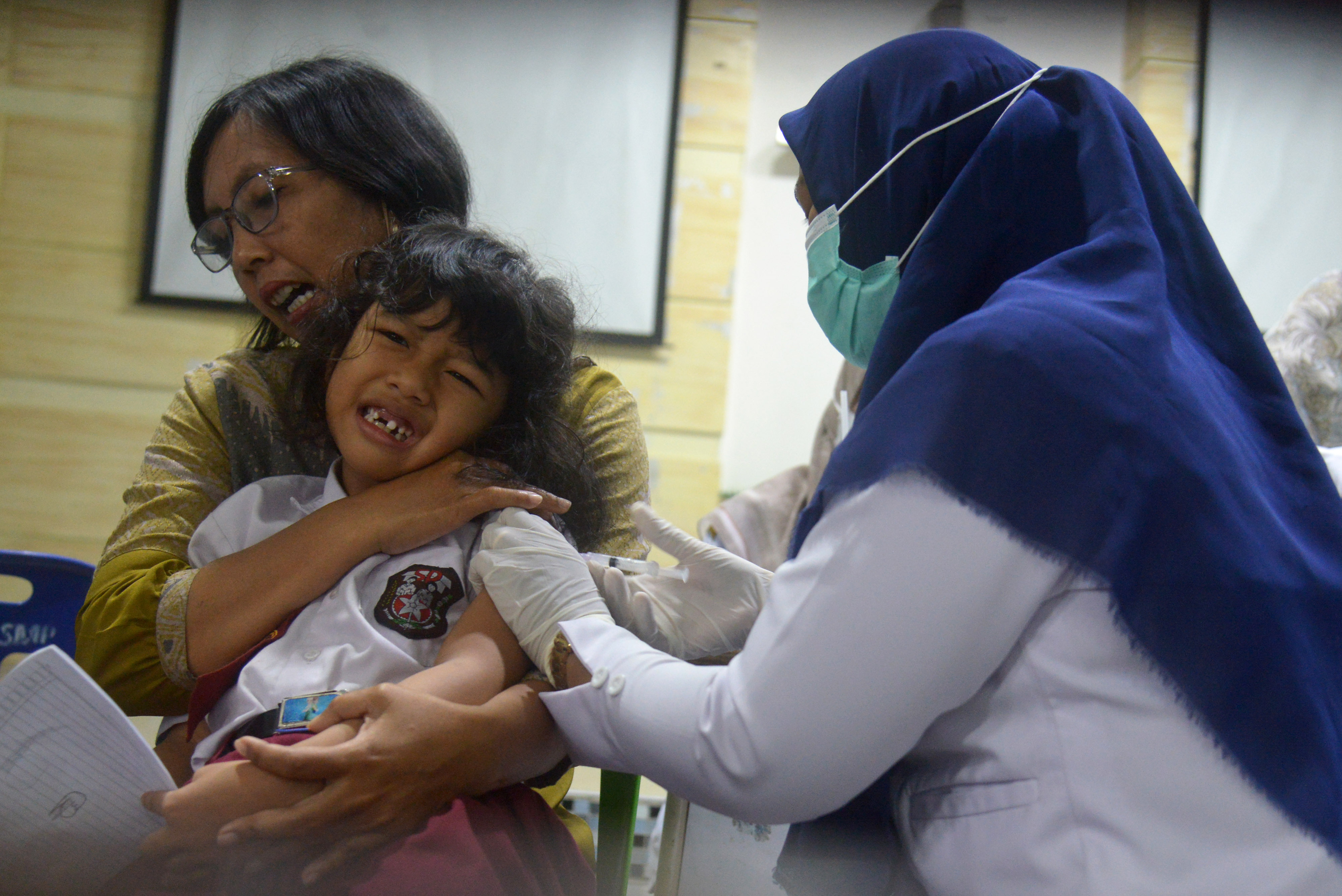 Petugas kesehatan menyuntikkan vaksin kepada murid SD.