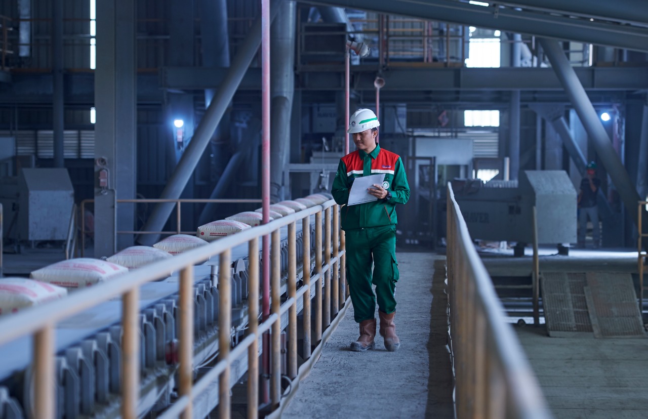 Seorang karyawan SMBR sedang mengecek produksi semen di pabrik.