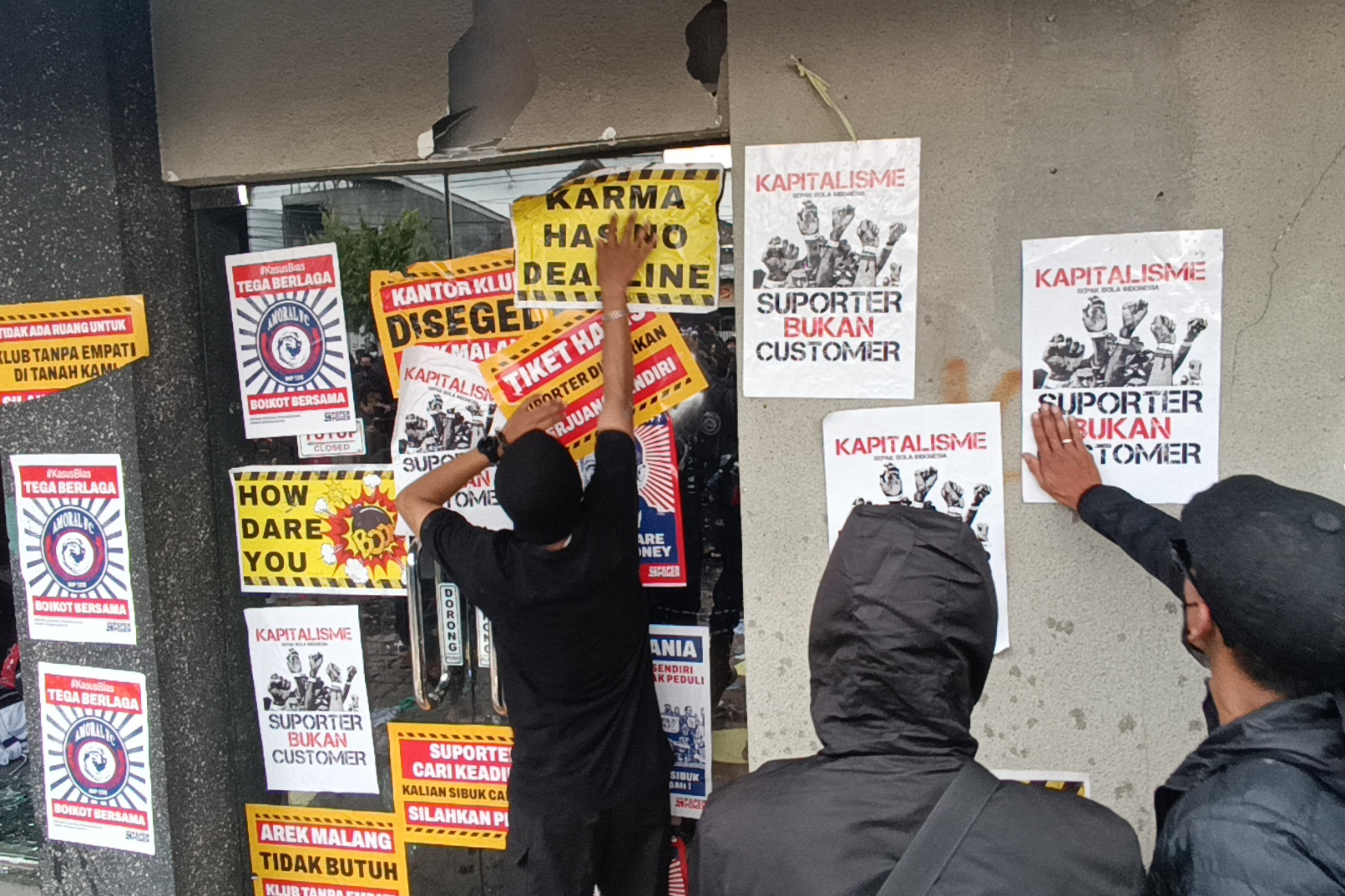Sejumlah pengunjuk rasa yang tergabung dalam Arek Malang Bersikap menempelkan poster saat berunjuk rasa di depan Kantor Tim Arema FC.