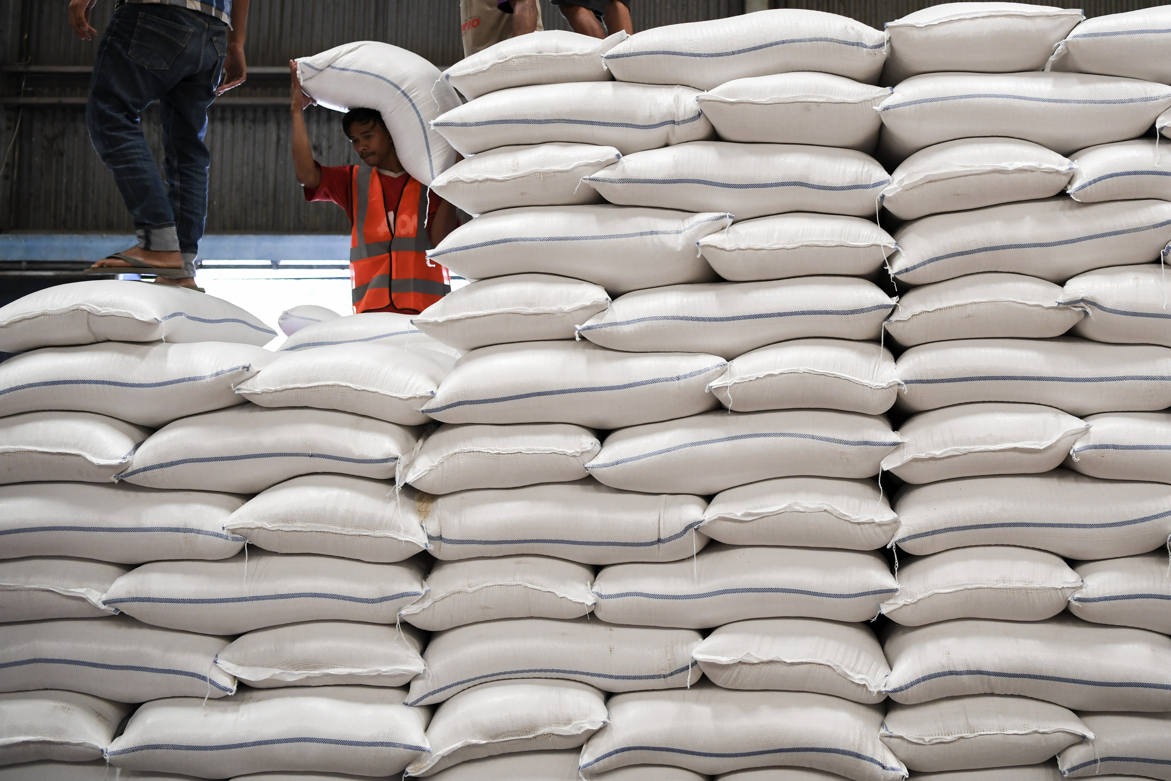Pekerja mengangkut karung berisi beras di gudang milik Perum Bulog.