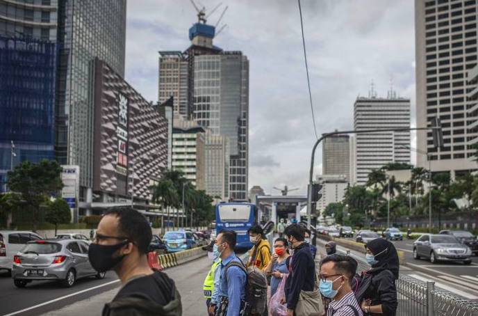 Warga bersiap menyeberang Jalan Jenderal Sudirman di Jakarta, Kamis (17/12/2020).