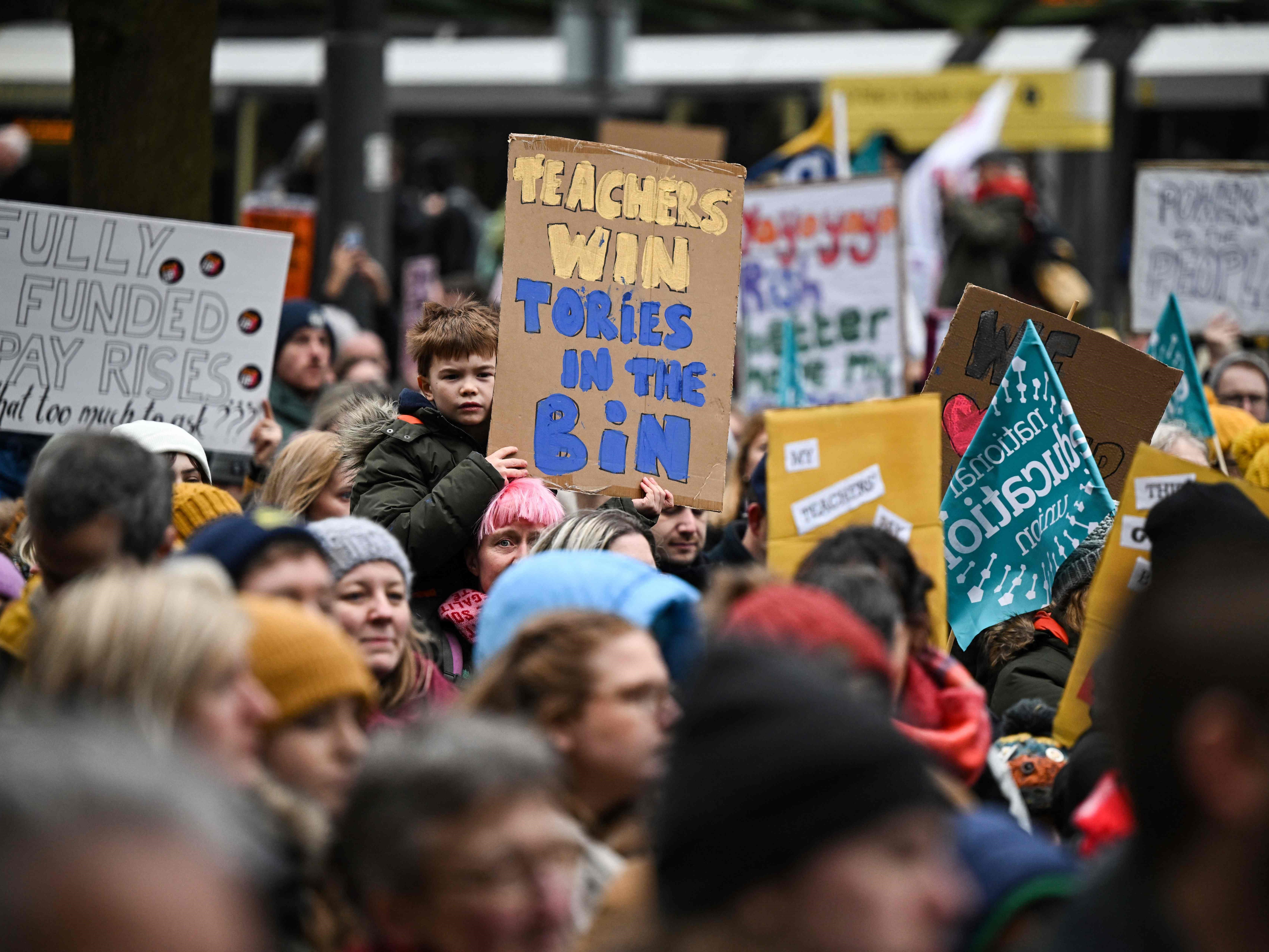 Guru memegang poster saat mereka mengambil bagian dalam protes yang diselenggarakan NEU dan serikat pekerja terafiliasi lain.