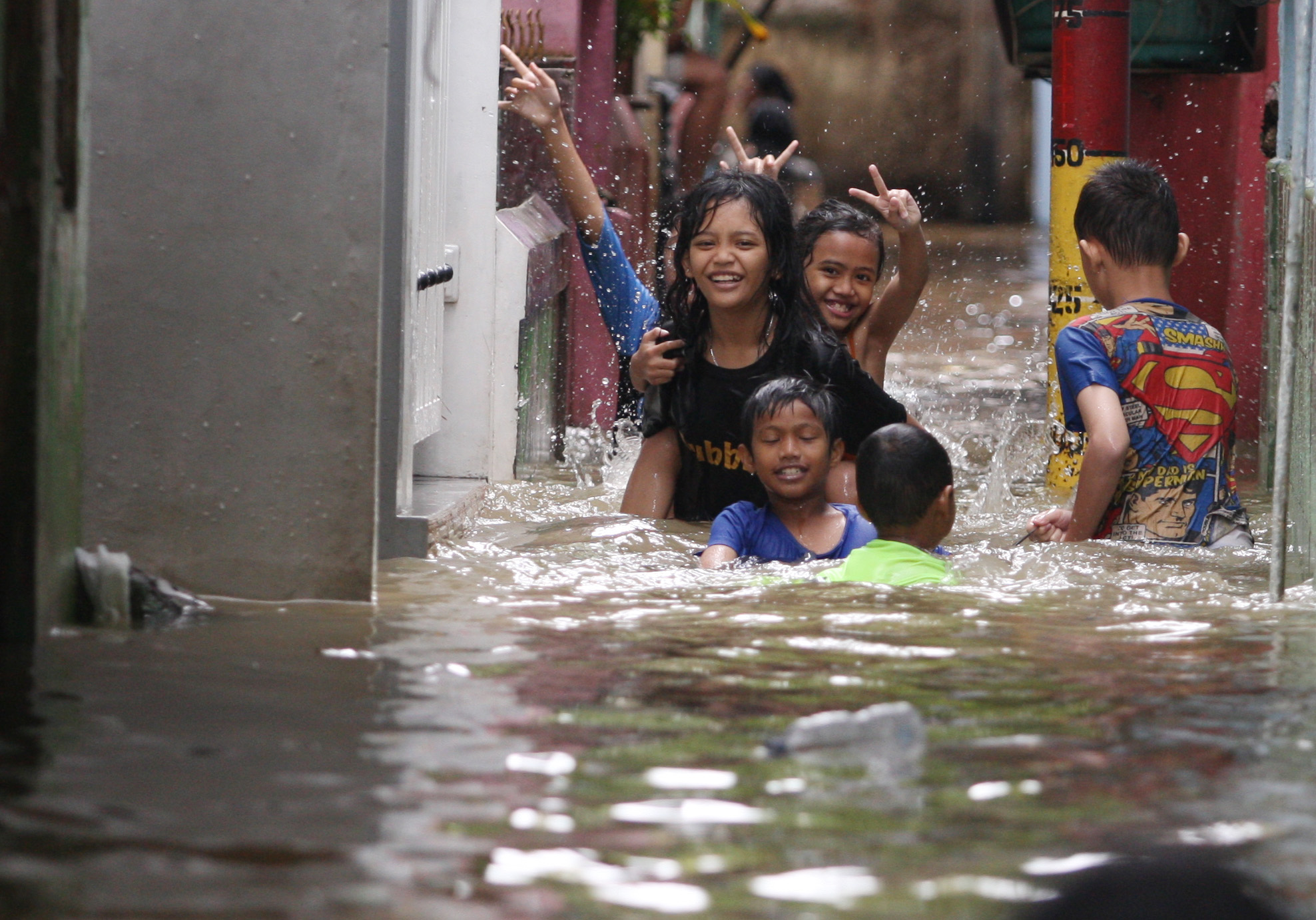 Anak-anak bermain di tengah banjir yang merendam kawasan Kebon Pala, Kecamatan Jatinegara, Jakarta Timur, Senin (27/2).