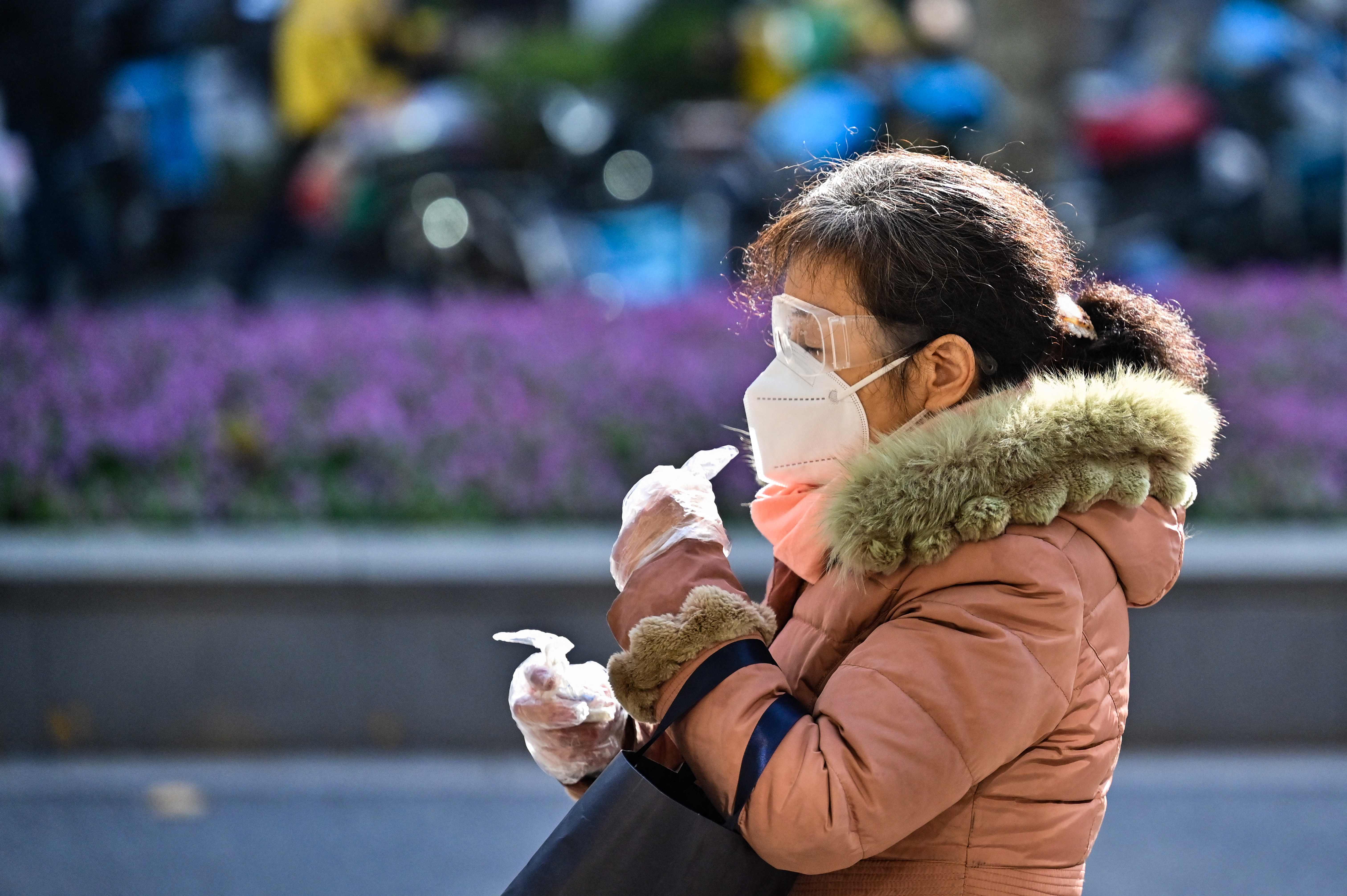 Seorang perempuan memakai masker di Distrik di  Jing'an, Tiongkok 