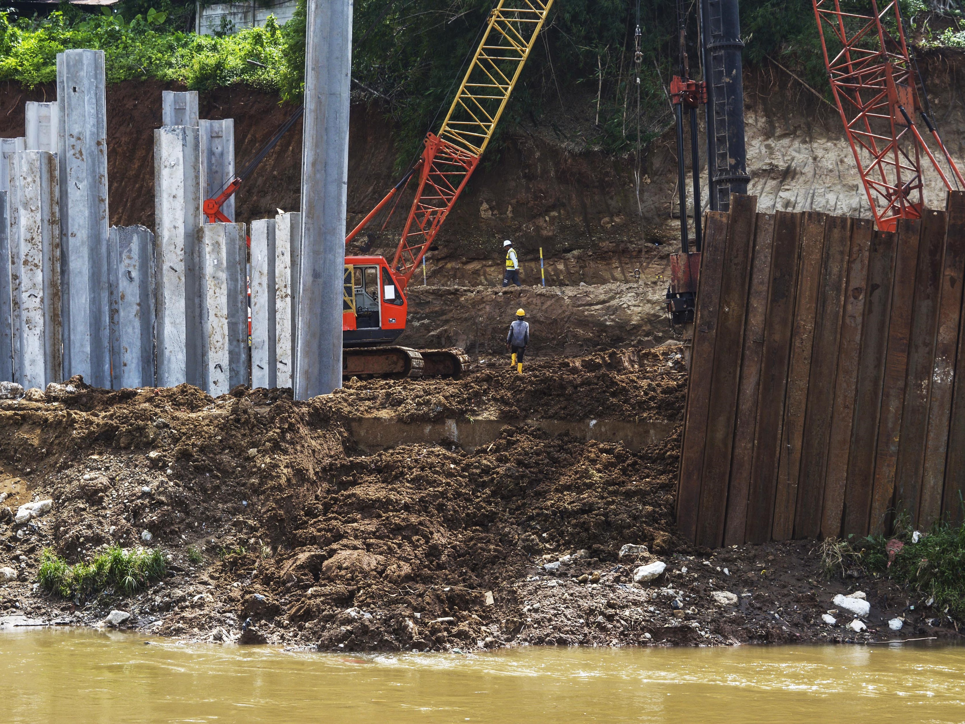 Pekerja dengan bantuan alat berat menyelesaikan pembangunan saringan sampah di Kali Ciliwung, Jagakarsa, Jakarta, Rabu (16/11/2022).