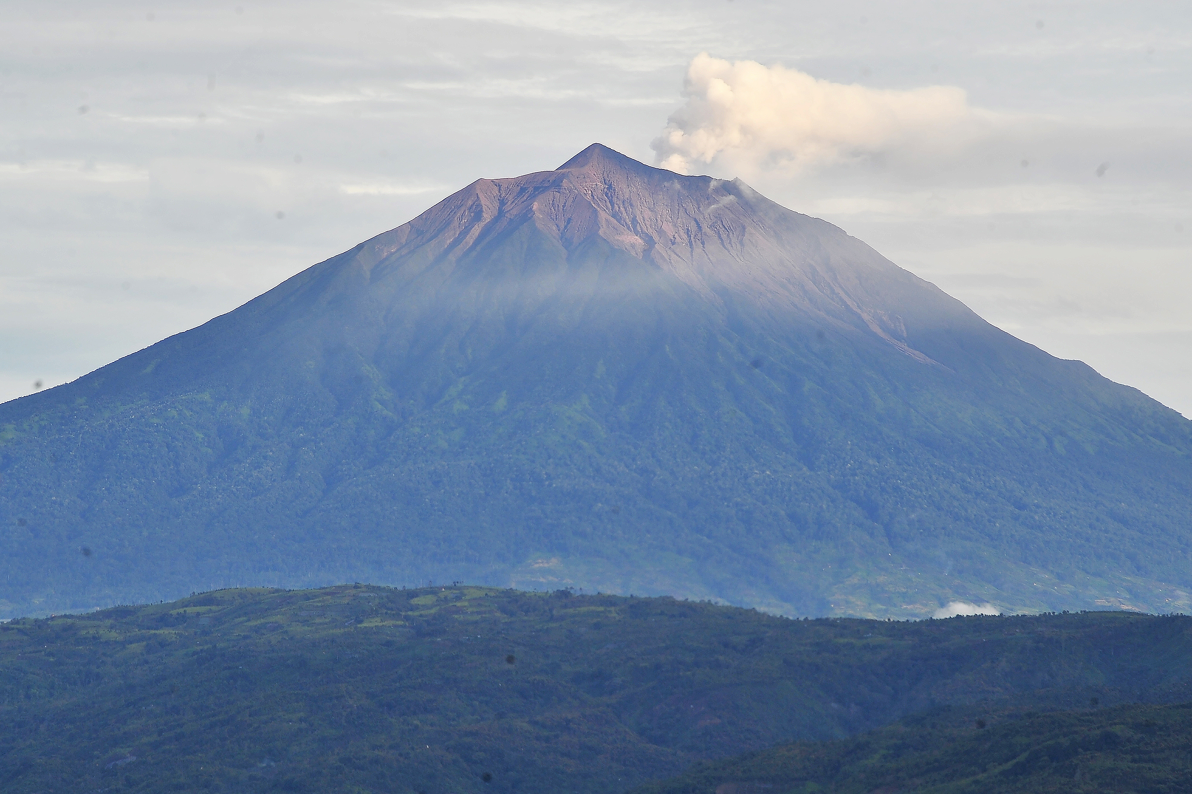 Potret Gunung Kerinci yang mengembuskan gas dan material ke udara.