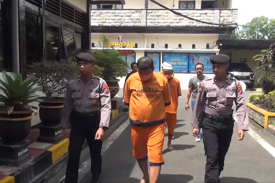 Polisi mengawal para tersangka.