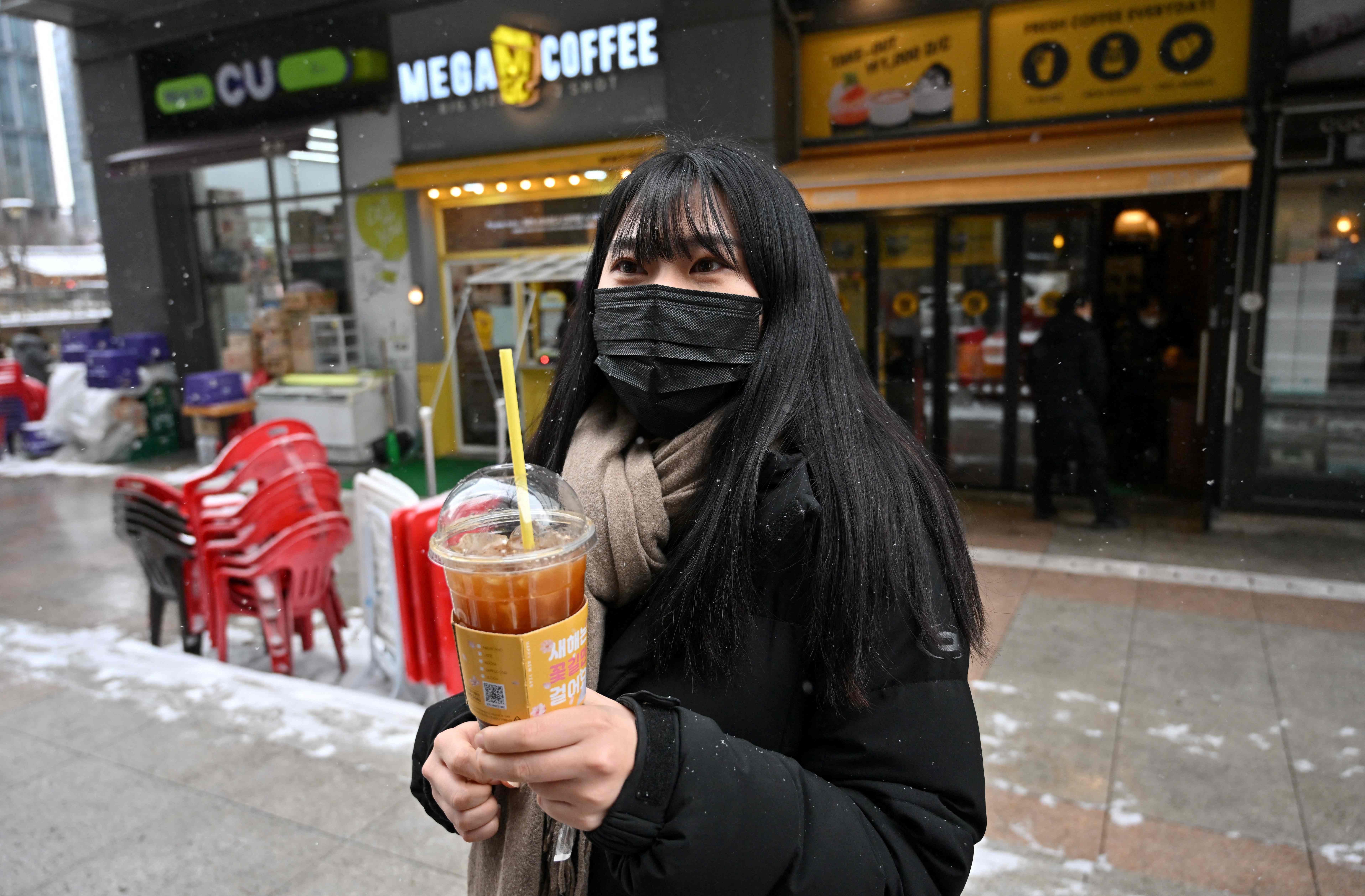 Seorang pekerja Korsel memegang iced Americano di Seoul saat akhir Januari yang dingin.