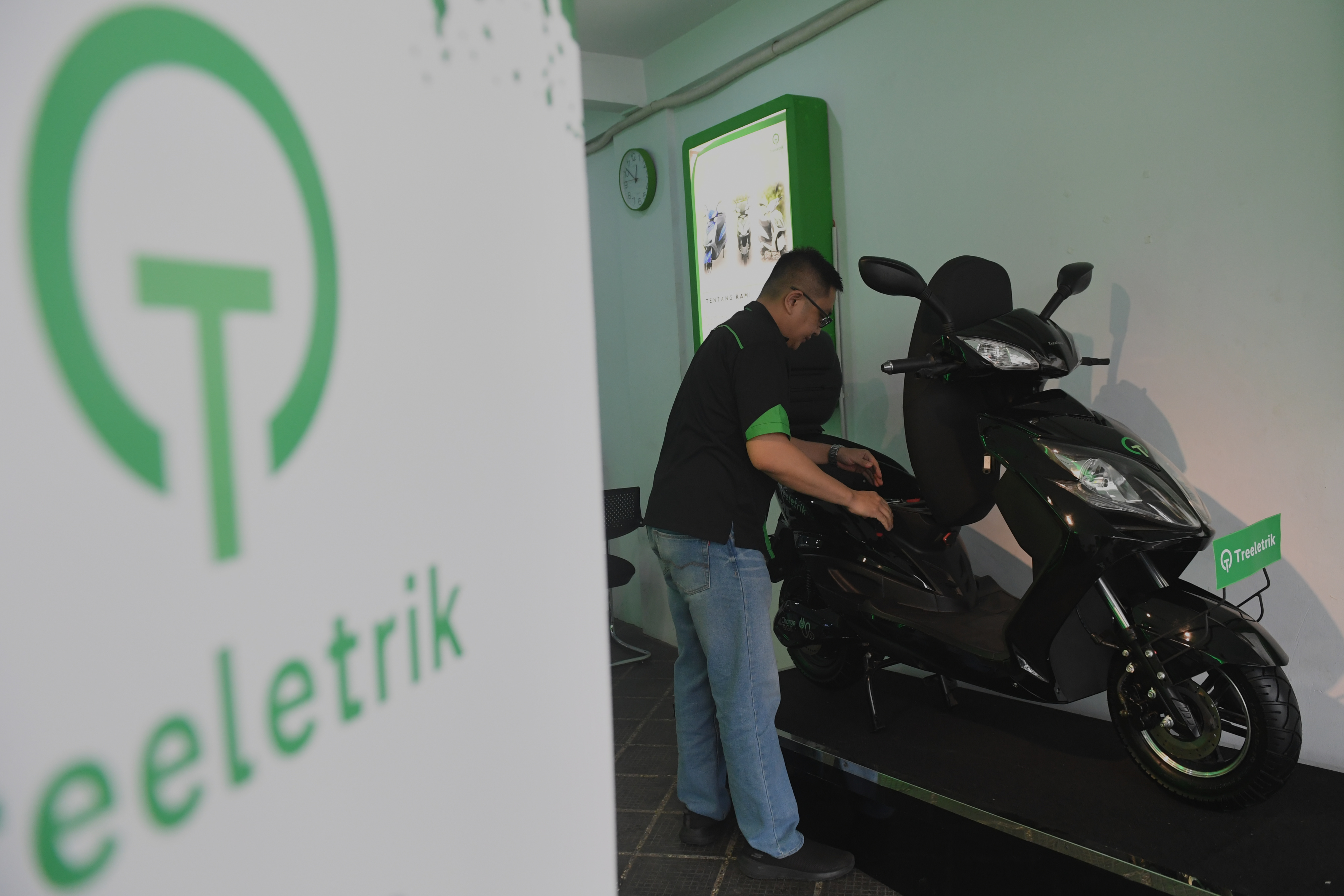 Pekerja memeriksa motor listrik yang dijual di salah satu showroom.