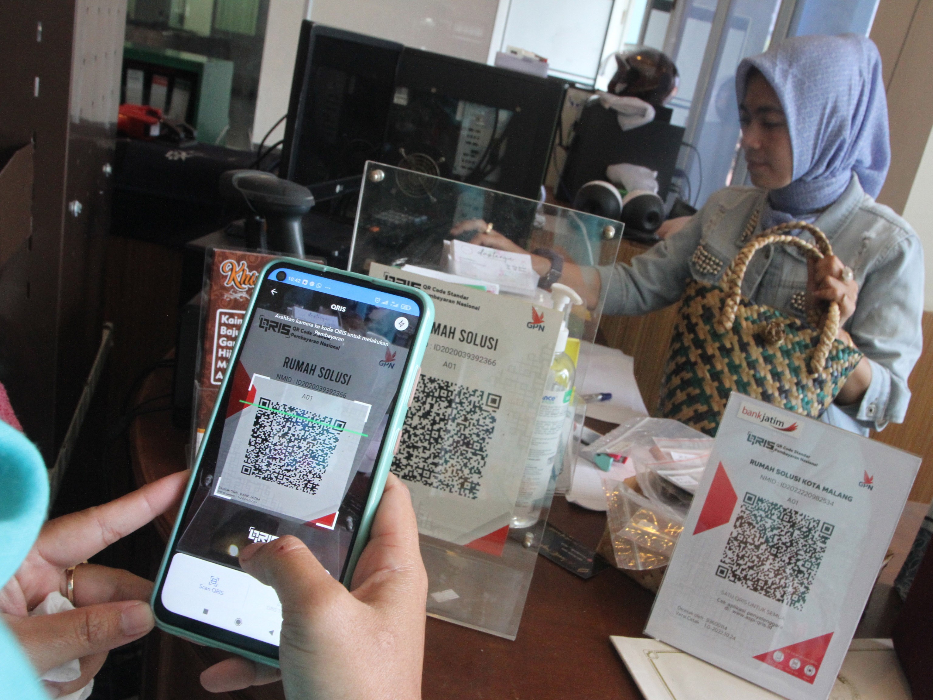 Seorang konsumen menggunakan layanan pembayaran digital QRIS saat membeli produk di gerai Rumah Solusi UMKM, Malang, Jatim, Kamis (12/1).